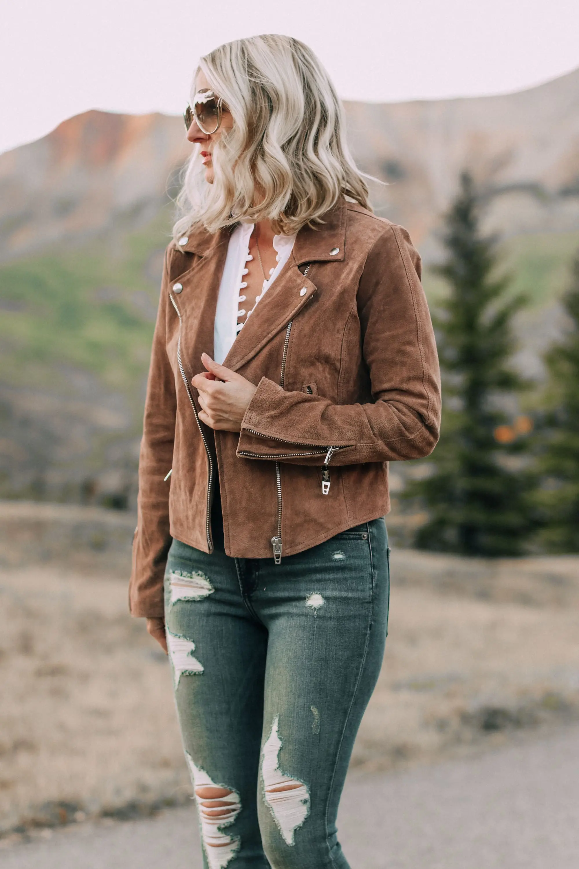 Suede moto jacket by BlankNYC on fashion blogger Erin Busbee of Busbee Style paired with Express white blouse and distressed jeans with beige Vince Camuto booties and Chloe sunglasses in Telluride, Colorado