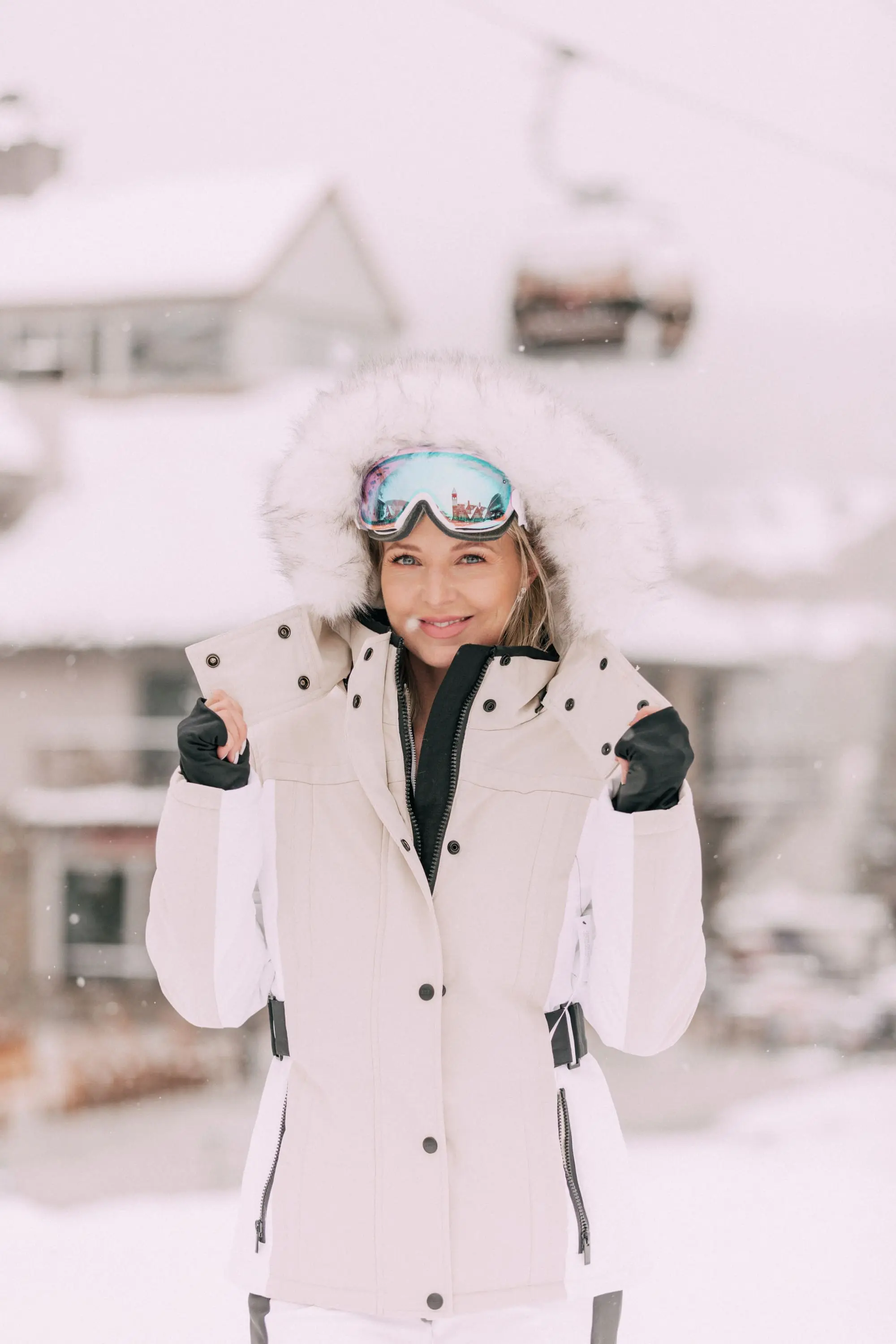Chic Ski Gear, Fashion Blogger Over 40 Erin Busbee of BusbeeStyle.com wearing a tan and white coat, white striped ski pants, and peach color block bodysuit by Topshop SNO from Nordstrom in Telluride, Colorado