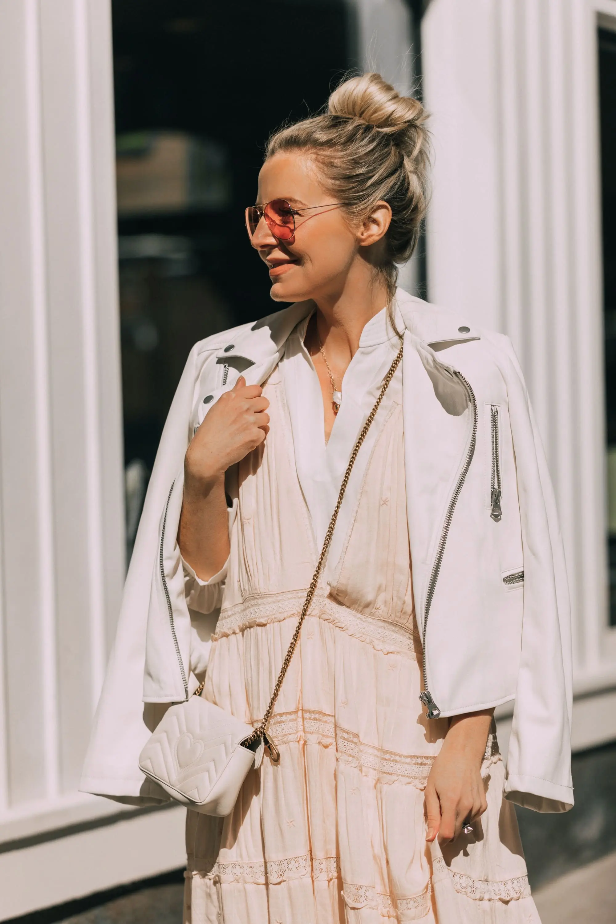 How To Wear A Maxi Dress, Fashion blogger Erin Busbee of BusbeeStyle.com wearing a peach Free People Lily of the Valley Maxi dress over a bubble sleeve white blouse by Frame, white cone heel booties, white crossbody bag, and white faux leather moto jacket from Scoop at Walmart walking in Telluride, Colorado