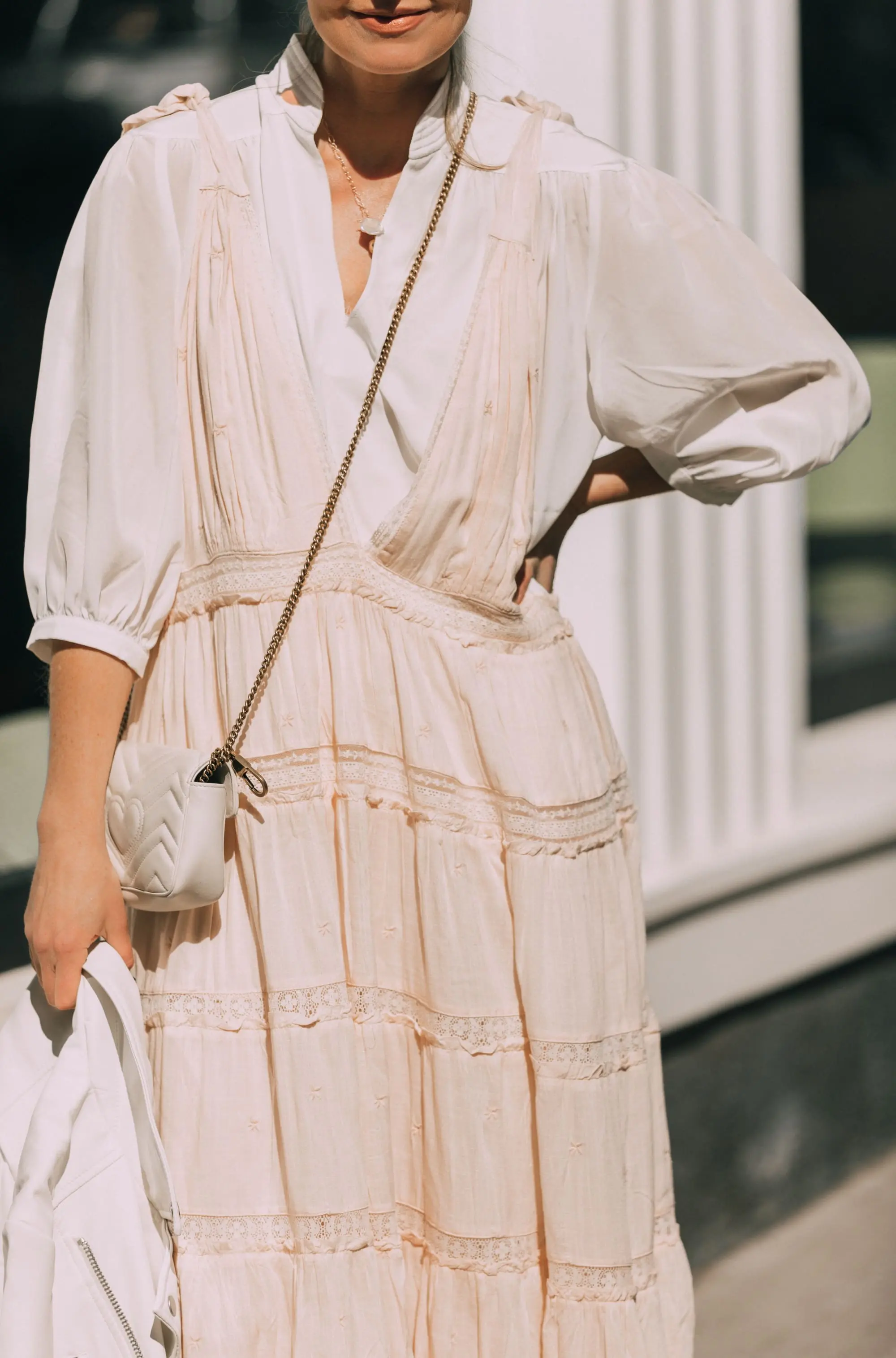 How To Wear A Maxi Dress, Fashion blogger Erin Busbee of BusbeeStyle.com wearing a peach Free People Lily of the Valley Maxi dress over a bubble sleeve white blouse by Frame, white cone heel booties, white crossbody bag, and white faux leather moto jacket from Scoop at Walmart walking in Telluride, Colorado