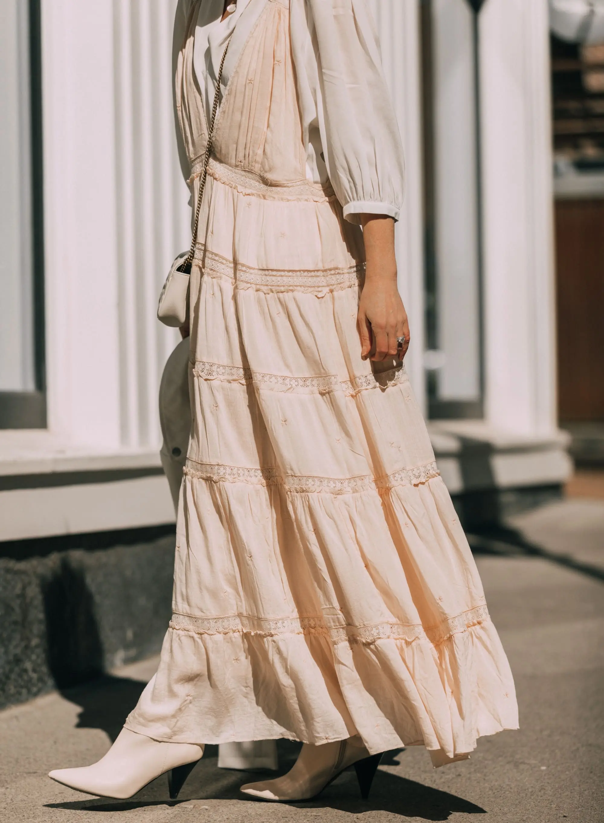 How To Wear A Maxi Dress, Fashion blogger Erin Busbee of BusbeeStyle.com wearing a peach Free People Lily of the Valley Maxi dress over a bubble sleeve white blouse by Frame, white cone heel booties, white crossbody bag, and white faux leather moto jacket from Scoop at Walmart walking in Telluride, Colorado