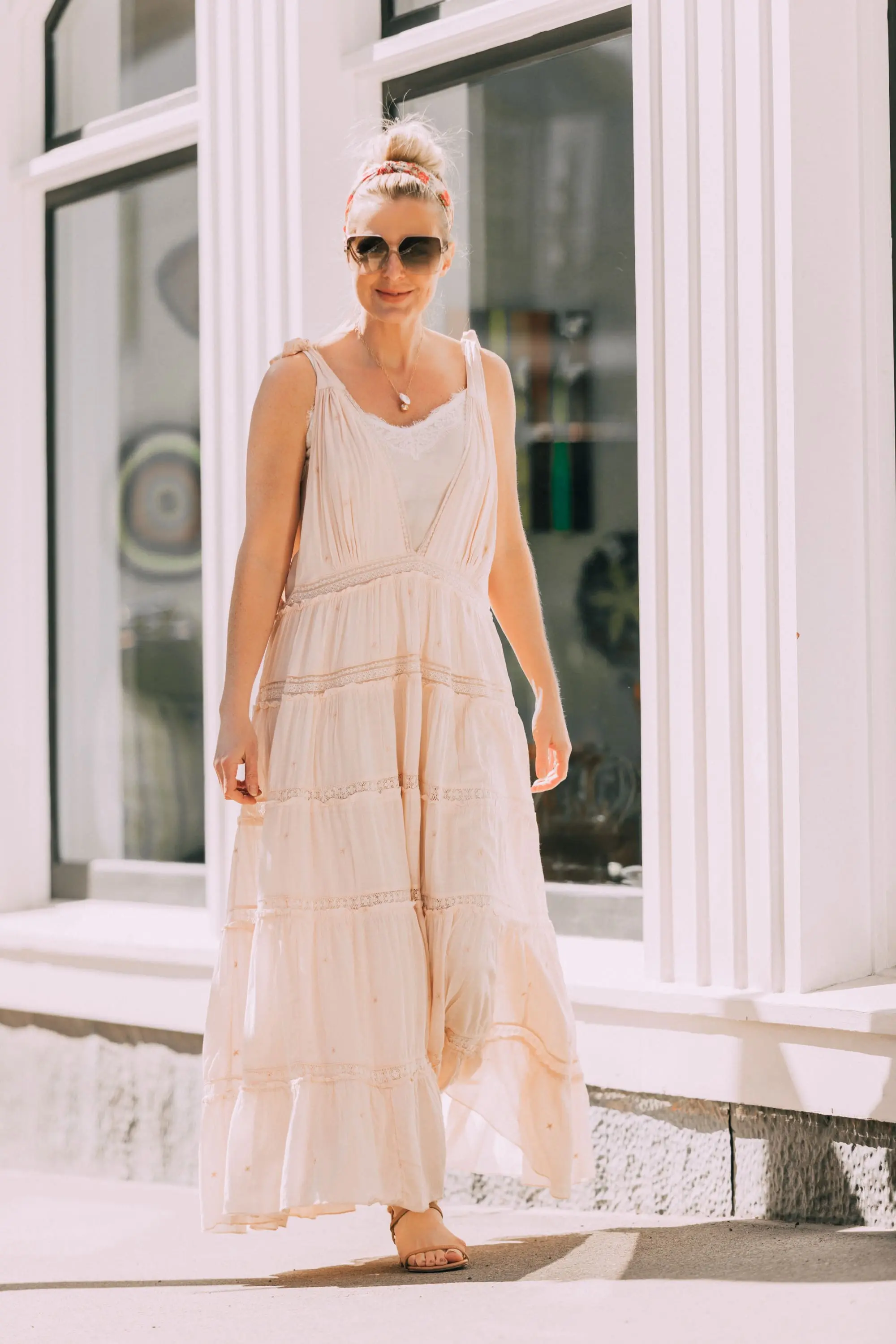 How To Wear A Maxi Dress, Fashion blogger Erin Busbee of BusbeeStyle.com wearing a peach Free People Lily of the Valley Maxi dress with brown block heel sandals, white lace cami underneath, floral headband, gold necklace, and sunglasses walking in Telluride, Colorado