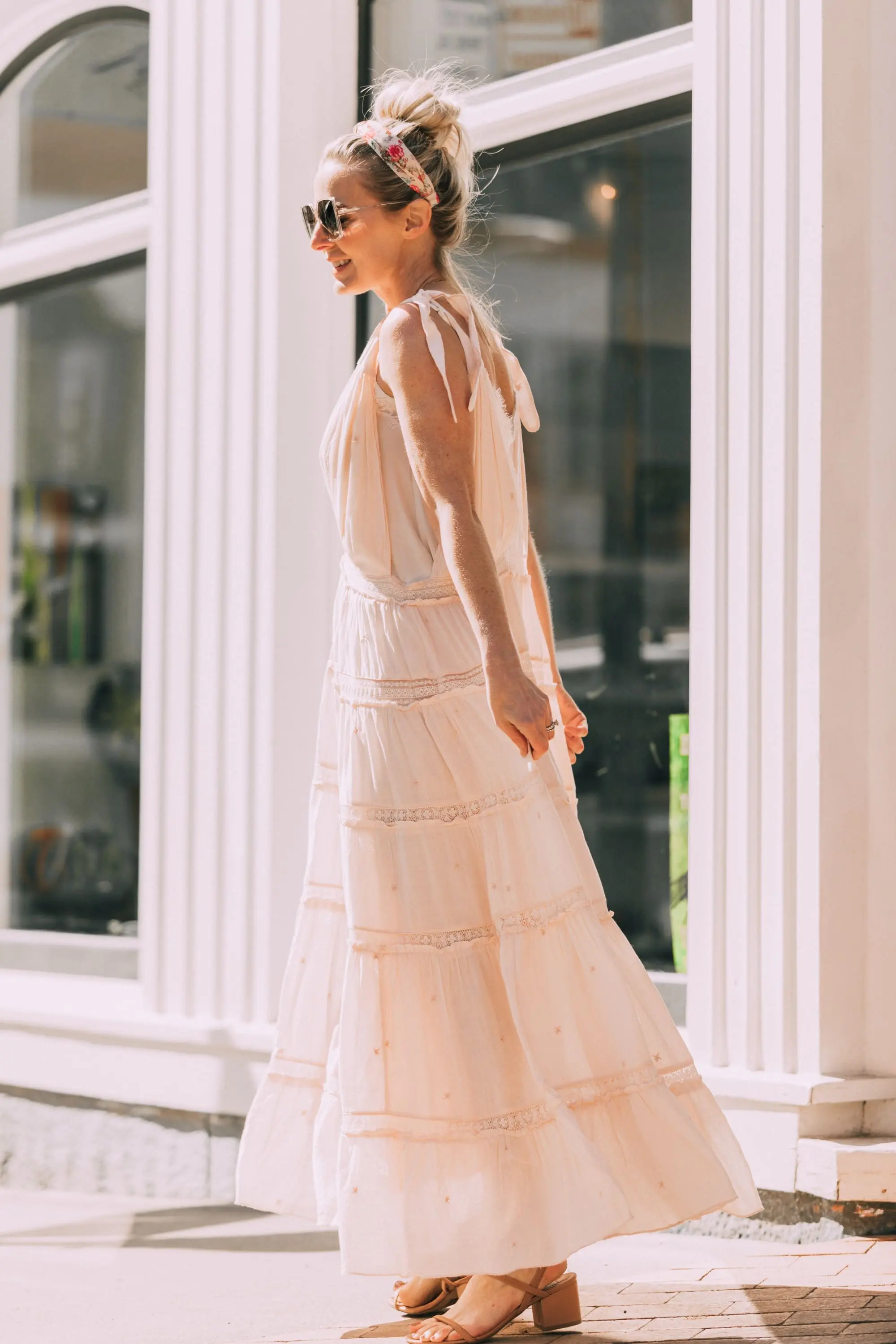 How To Wear A Maxi Dress, Fashion blogger Erin Busbee of BusbeeStyle.com wearing a peach Free People Lily of the Valley Maxi dress with brown block heel sandals, white lace cami underneath, floral headband, gold necklace, and sunglasses walking in Telluride, Colorado