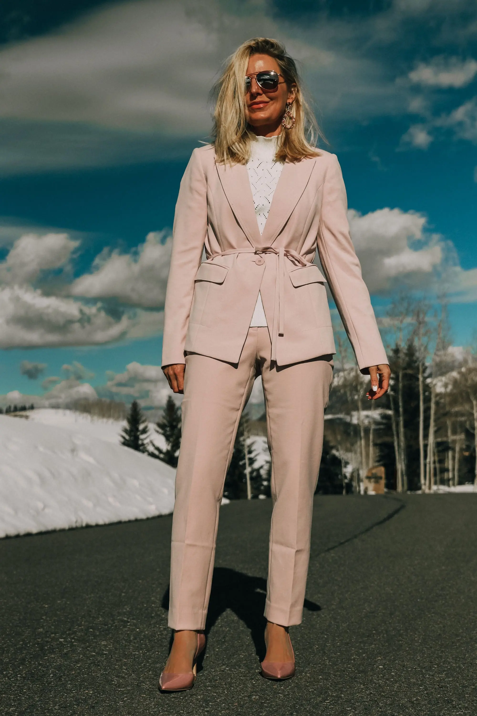 Pink Office Outfit, Fashion blogger Erin Busbee of BusbeeStyle.com wearing a pink power suit from White House Black Market, including a pink belted blazer, pink soft stretch pants, white puff sleeve sweater dress, pink pumps, pink earrings, and aviator sunglasses in Telluride, Colorado