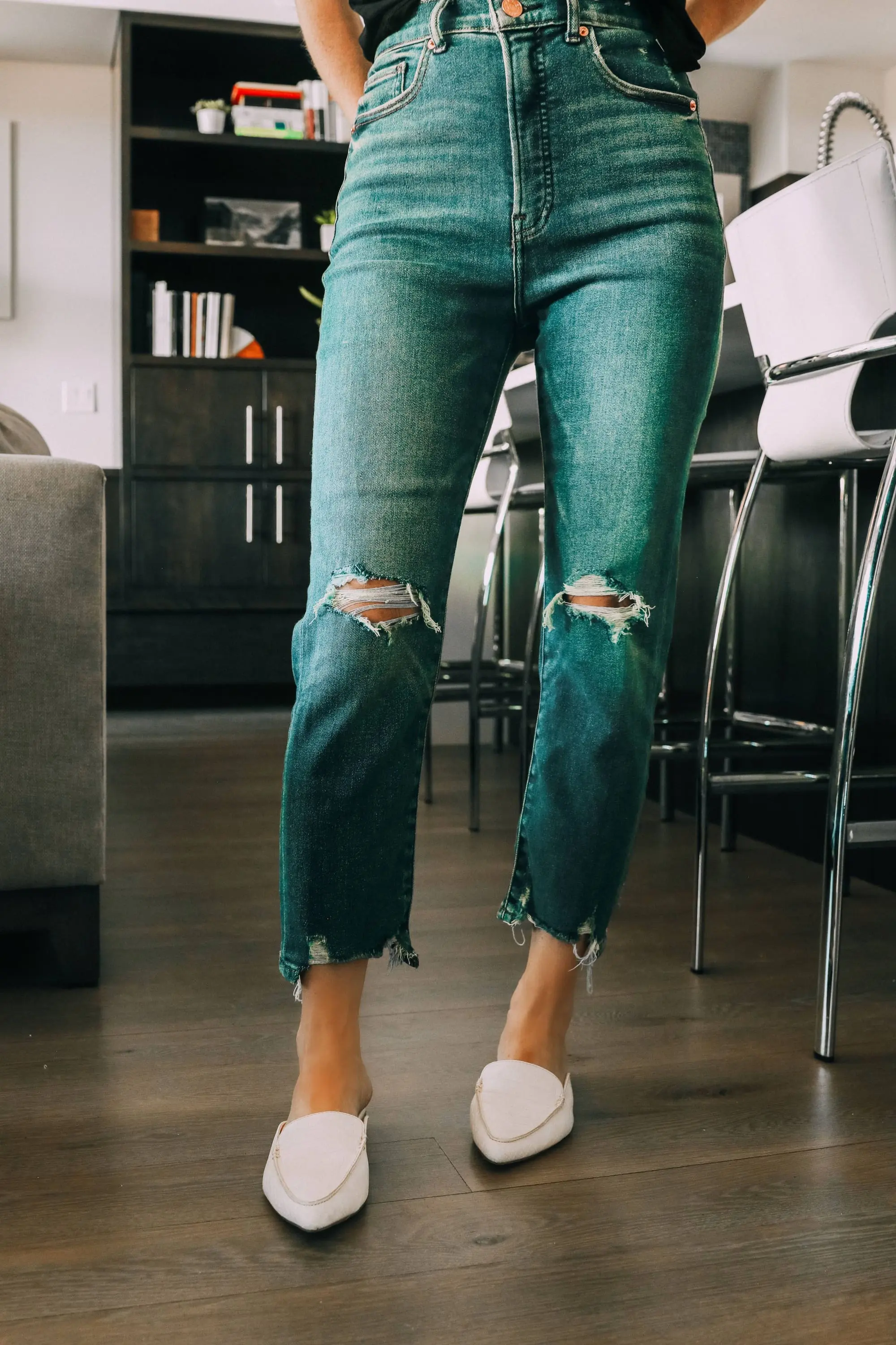 Work from home outfits that are affordable from Express featuring high rise distressed mom jeans, white loafers, black mock neck ruffle cotton top and lightweight leaf earrings