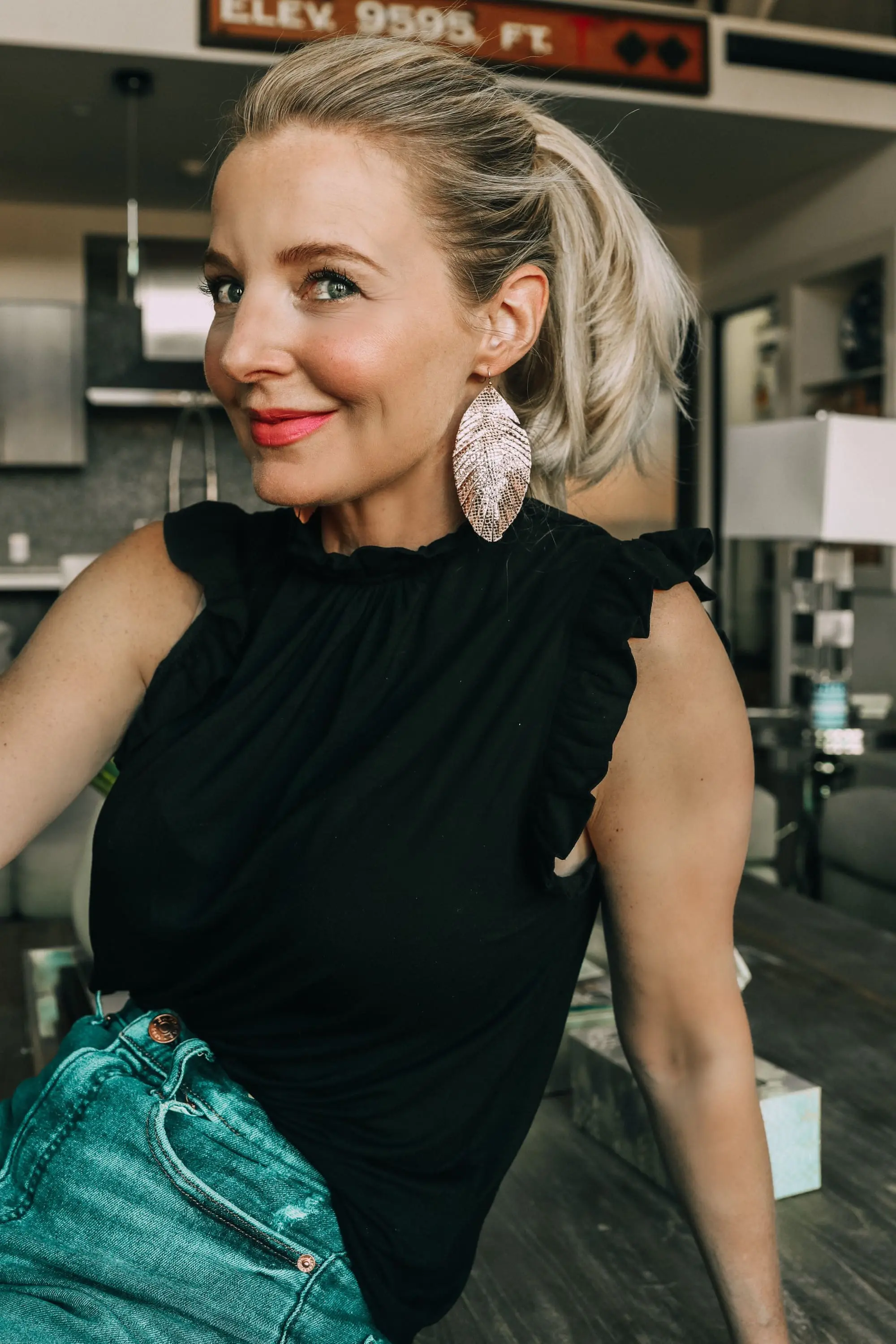 Work from home outfits that are affordable from Express featuring high rise distressed mom jeans, white loafers, black mock neck ruffle cotton top and lightweight leaf earrings