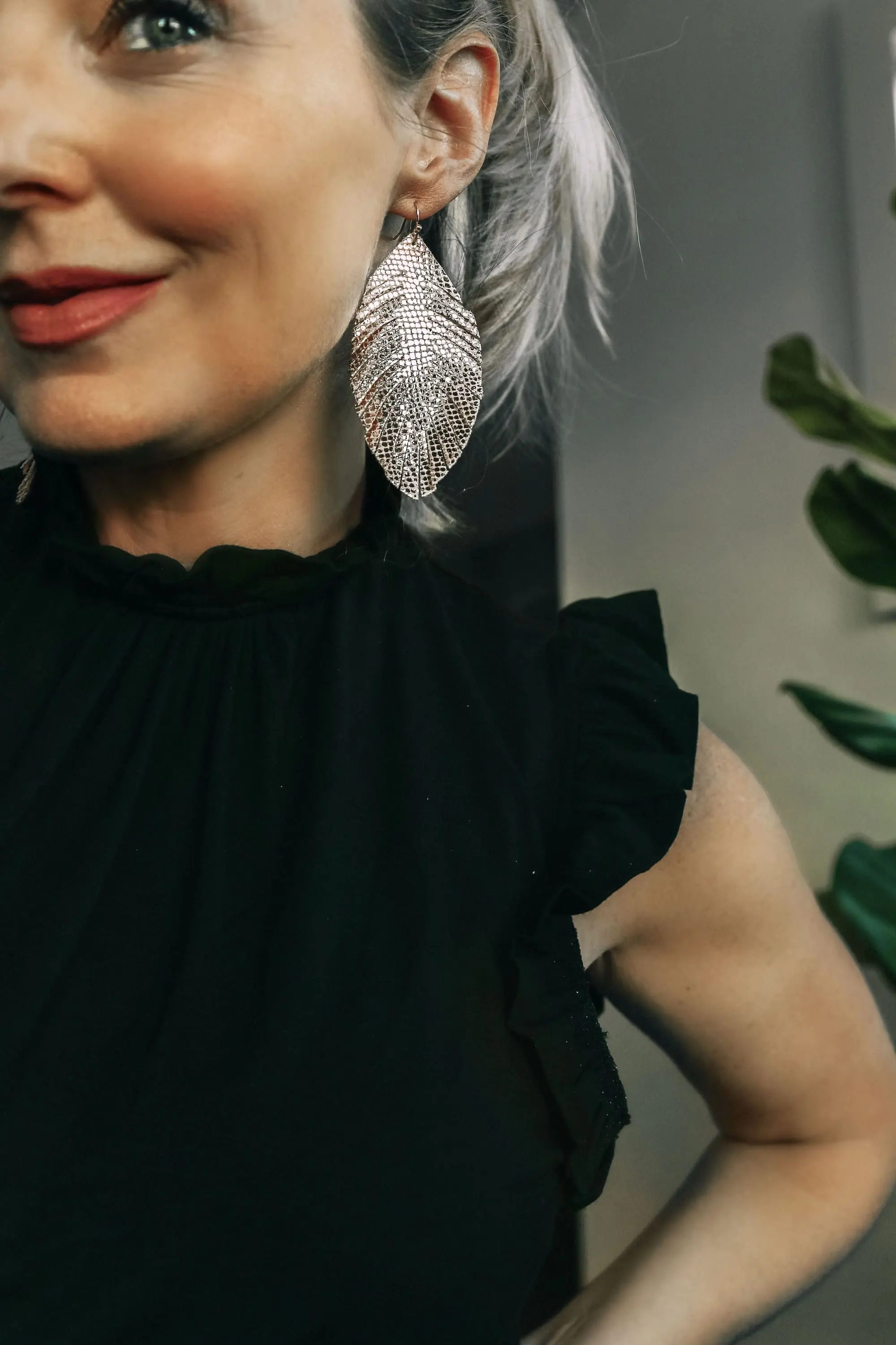 Work from home outfits that are affordable from Express featuring high rise distressed mom jeans, white loafers, black mock neck ruffle cotton top and lightweight leaf earrings