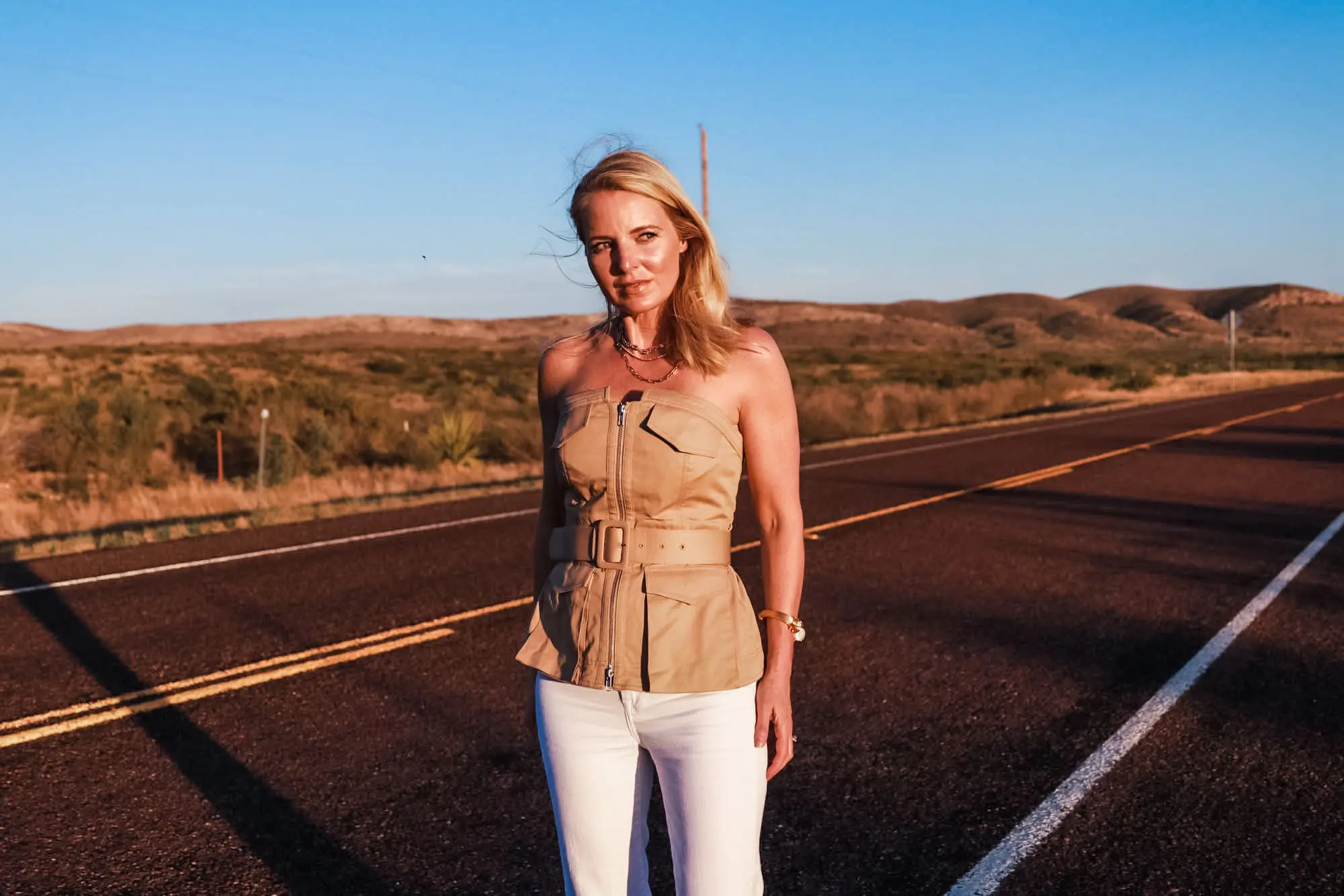 Africa Outfits, Erin Busbee of Busbee Style wearing a tan belted strapless utility trend shirt by Self Portrait with white flare jeans and See By Chloe wedges in Texas