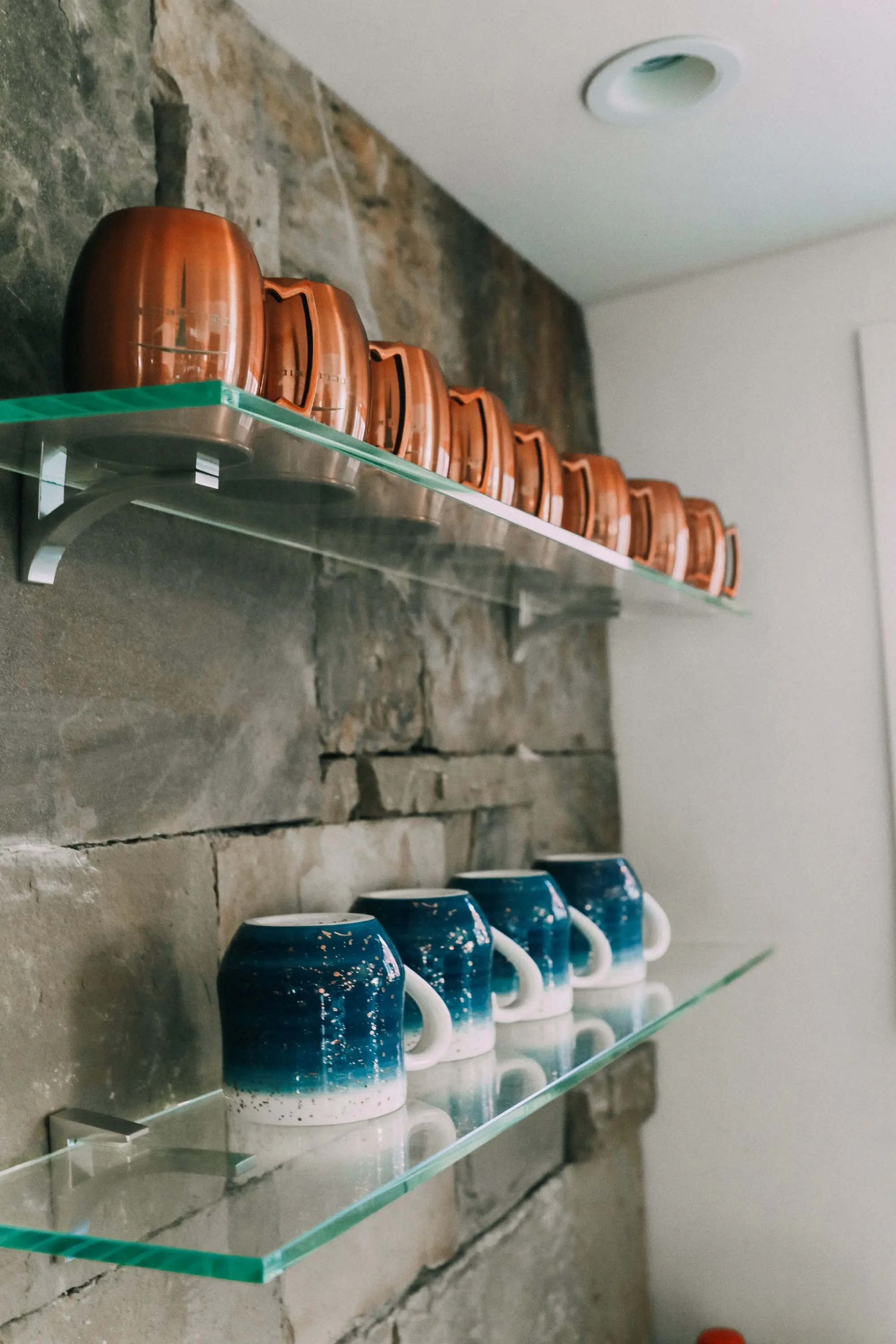 coffee mugs on open shelving above wet bar