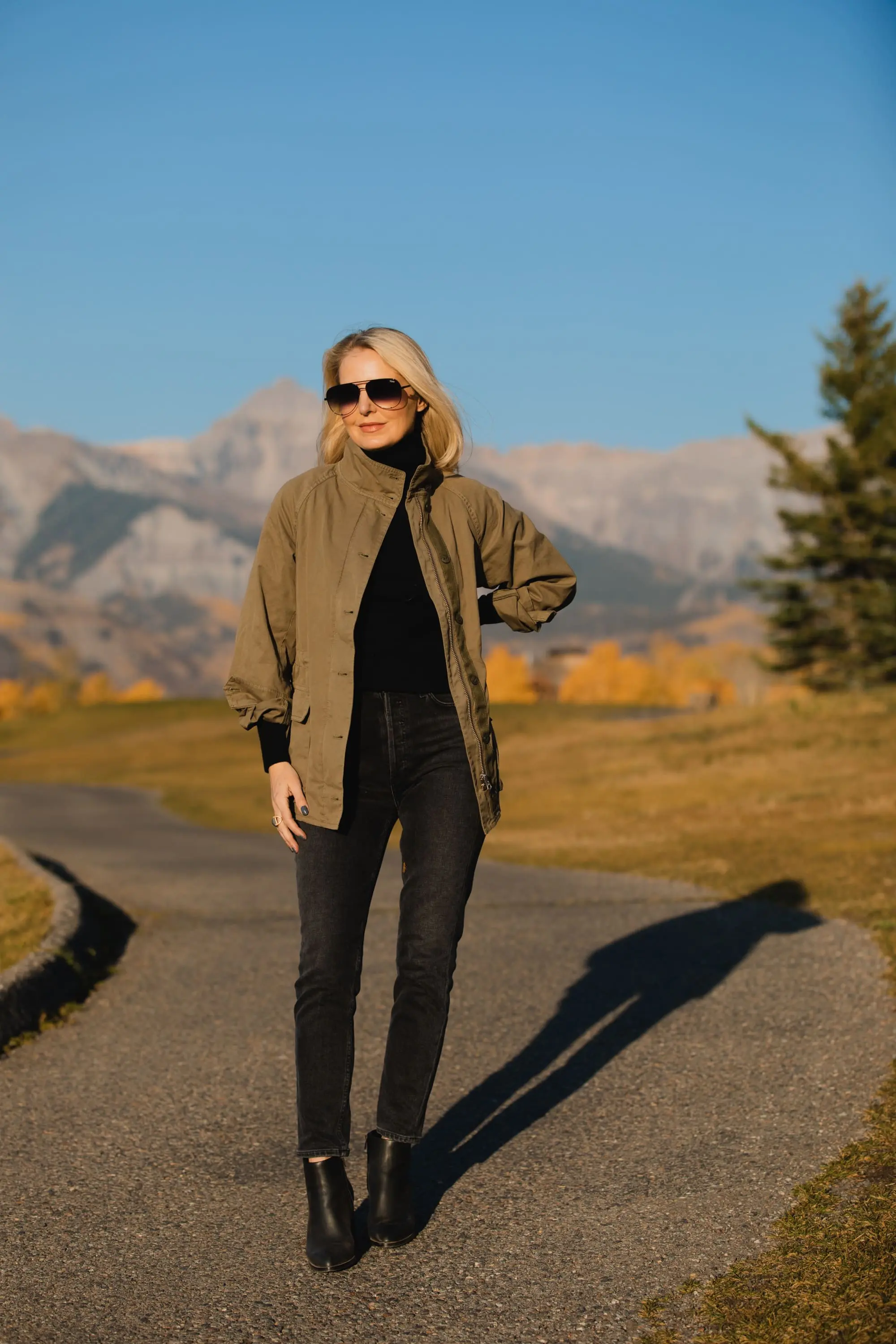 How To Wear A Cargo Jacket, Erin Busbee of Busbee Style wearing a green cargo jacket by rag & bone, black turtleneck puff sleeve cashmere sweater by Aqua, gray wash Nico slim fit jeans by Agolde, QUAY sunglasses, and Alexander Wang cutout booties in Telluride, Colorado