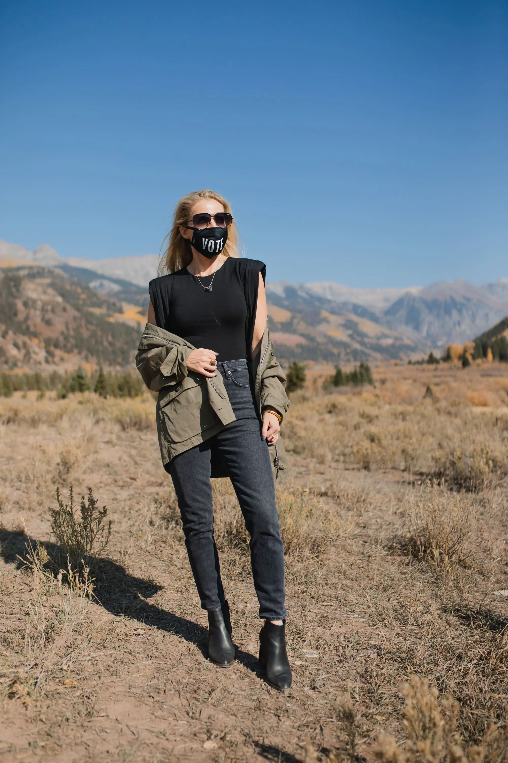 How To Wear A Cargo Jacket, Erin Busbee of Busbee Style wearing a green cargo jacket by rag & bone, black muscle tee tank by Aqua, gray wash Nico slim fit jeans by Agolde, QUAY sunglasses, Vote mask, and Alexander Wang cutout booties from Bloomingdale's in Telluride, Colorado