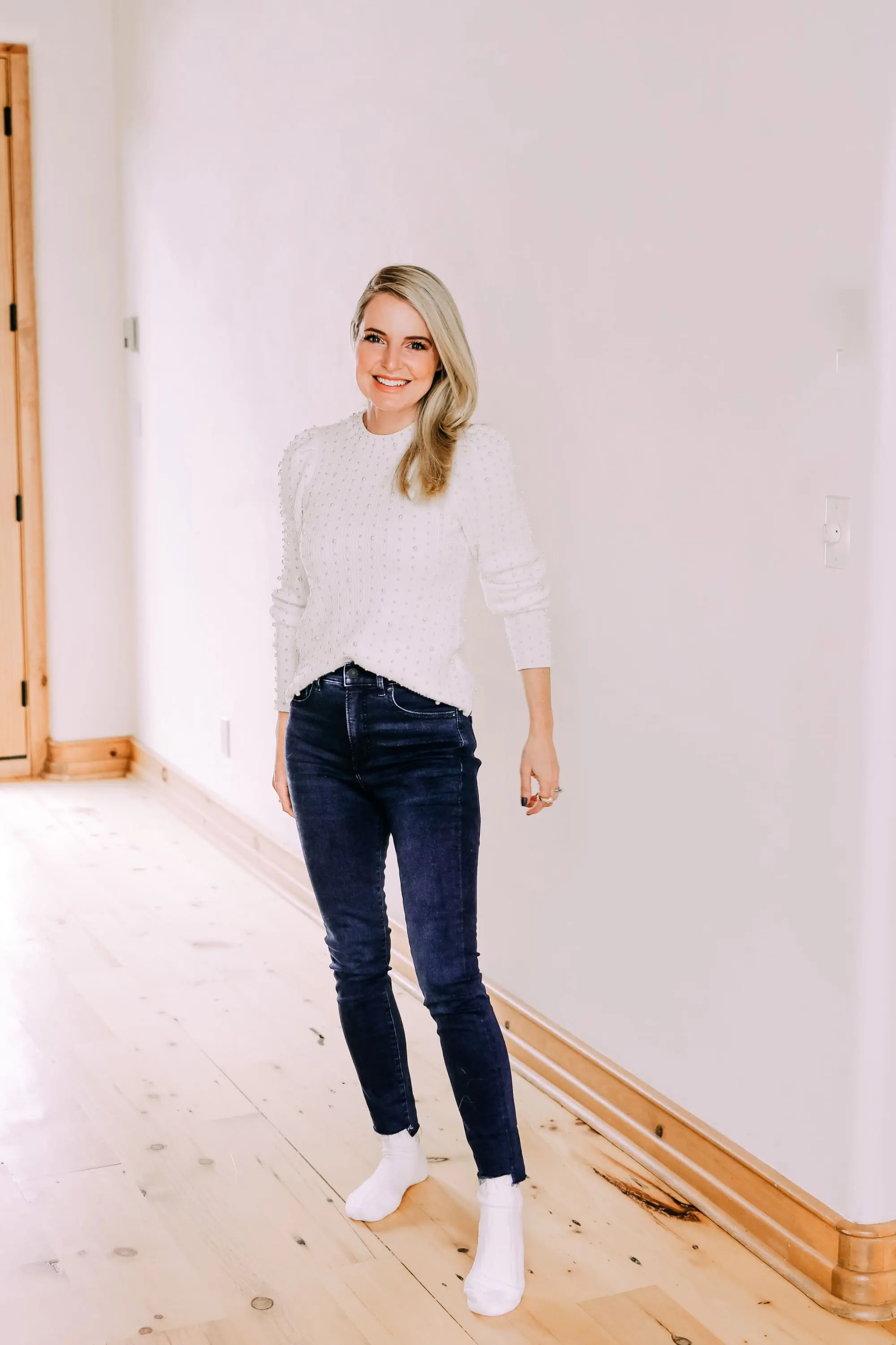 Black Friday Doorbuster, Erin Busbee of Busbee Style wearing a pearl embellished white sweater, raw step hem jeans, and cozy socks from Express in Telluride, Colorado