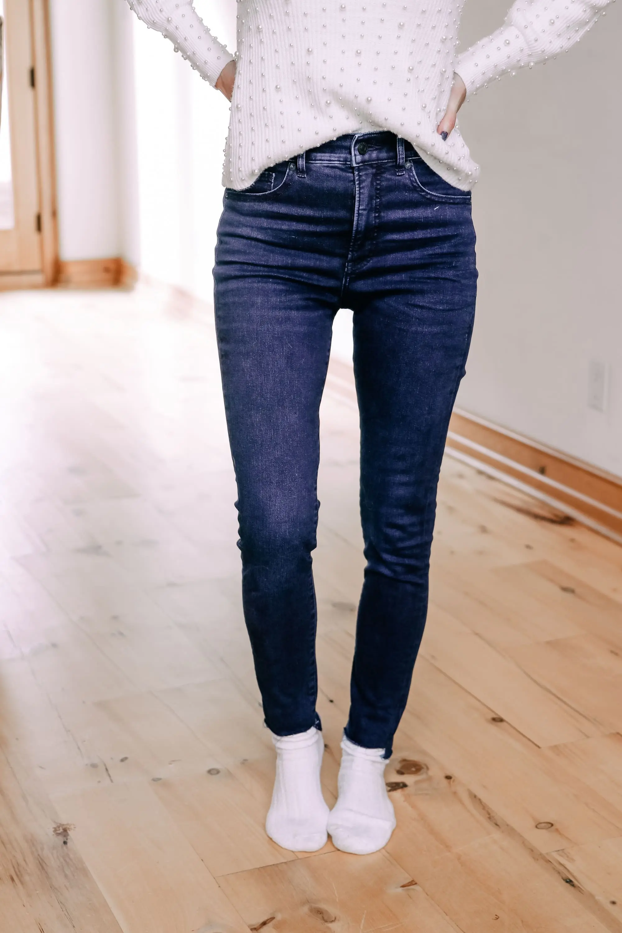 Black Friday Doorbuster, Erin Busbee of Busbee Style wearing a pearl embellished white sweater, raw step hem jeans, and cozy socks from Express in Telluride, Colorado