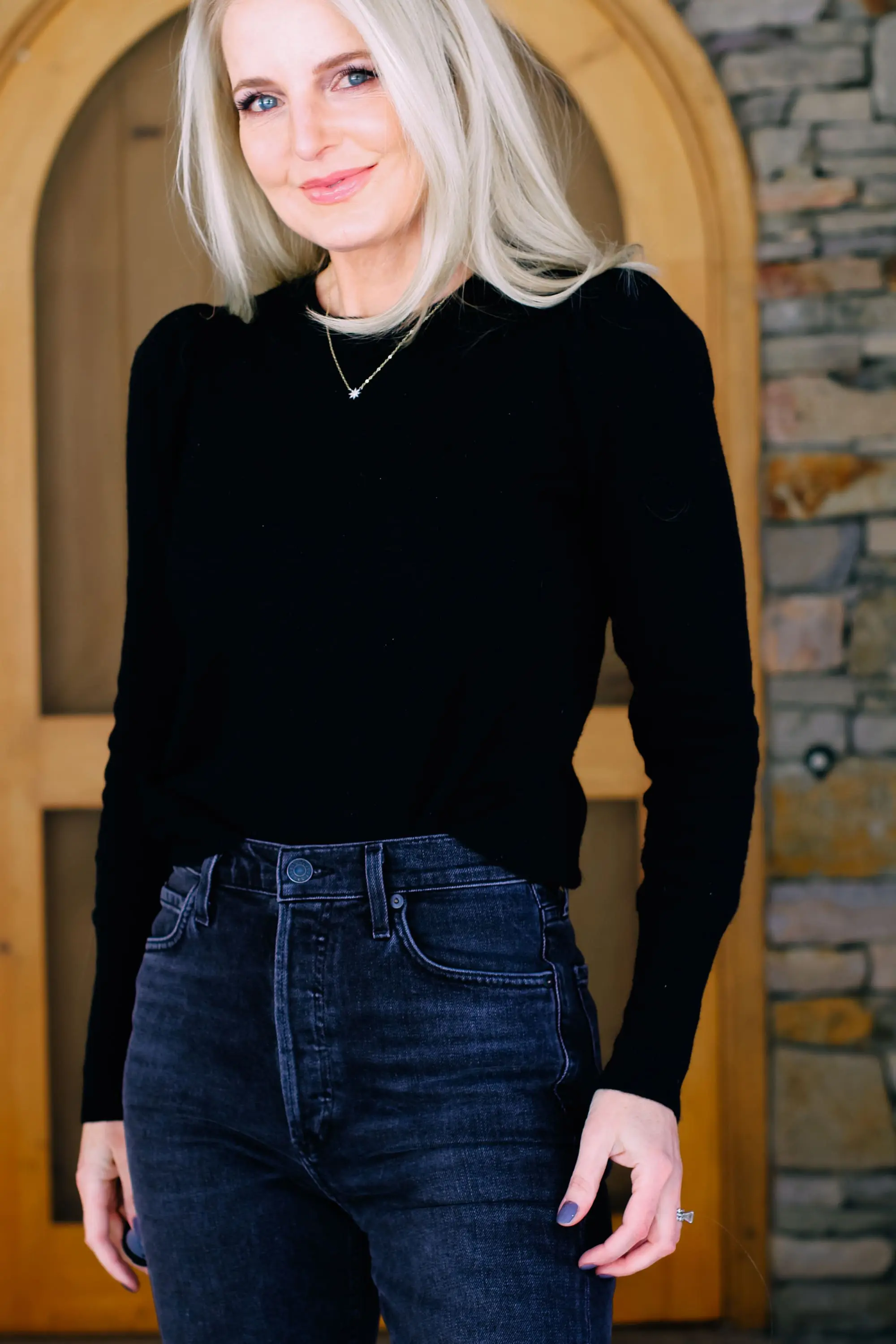 Thoughtful Gifts, Erin Busbee of Busbee Style wearing a black puff sleeve cashmere sweater by AQUA, gray wash Agolde jeans, black Sorel boots, and a diamond star necklace by Marc & Marcella from Bloomingdale's in Telluride, Colorado