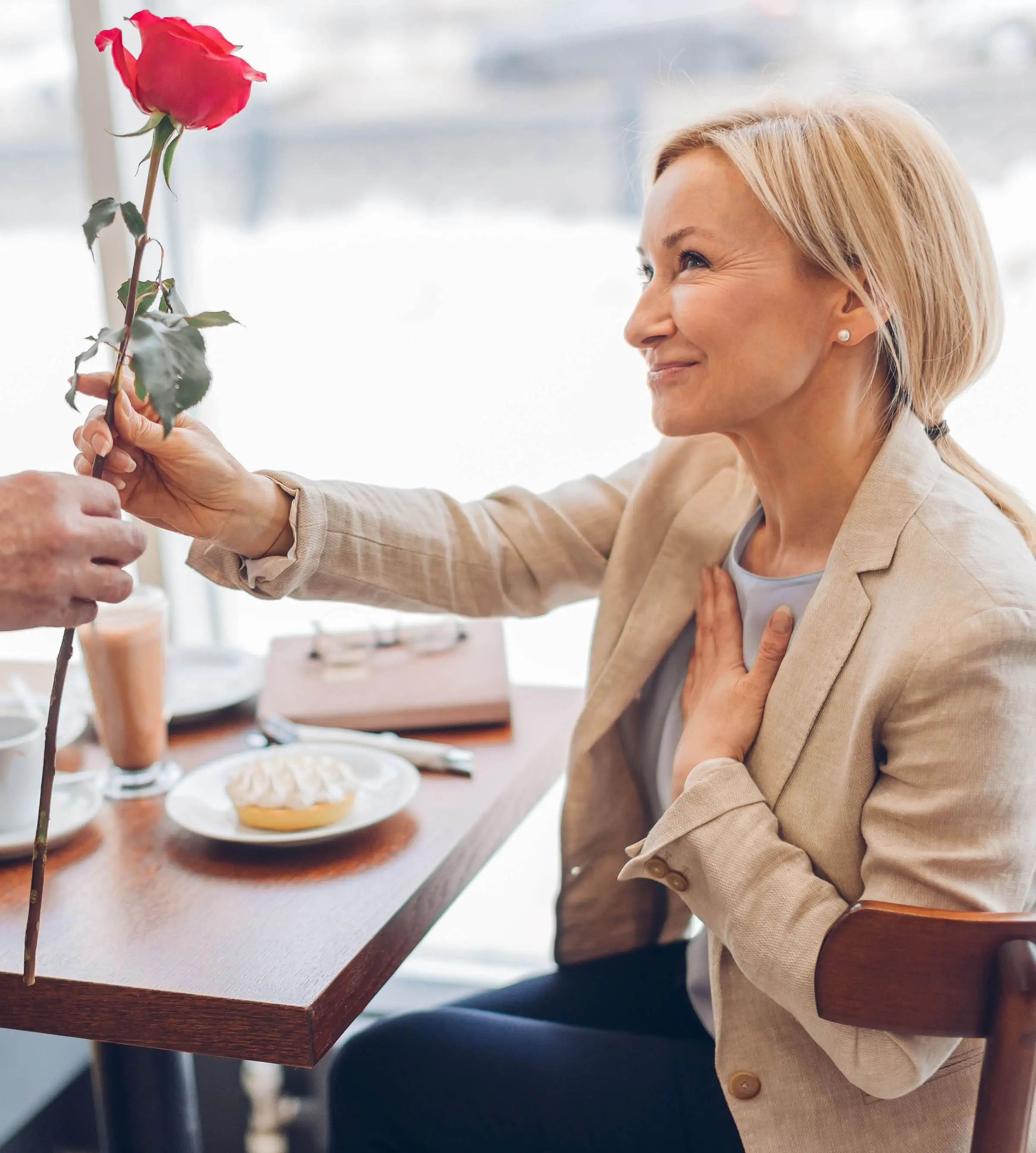 dating over 40, elegant woman receiving a rose from her date in a restaurant