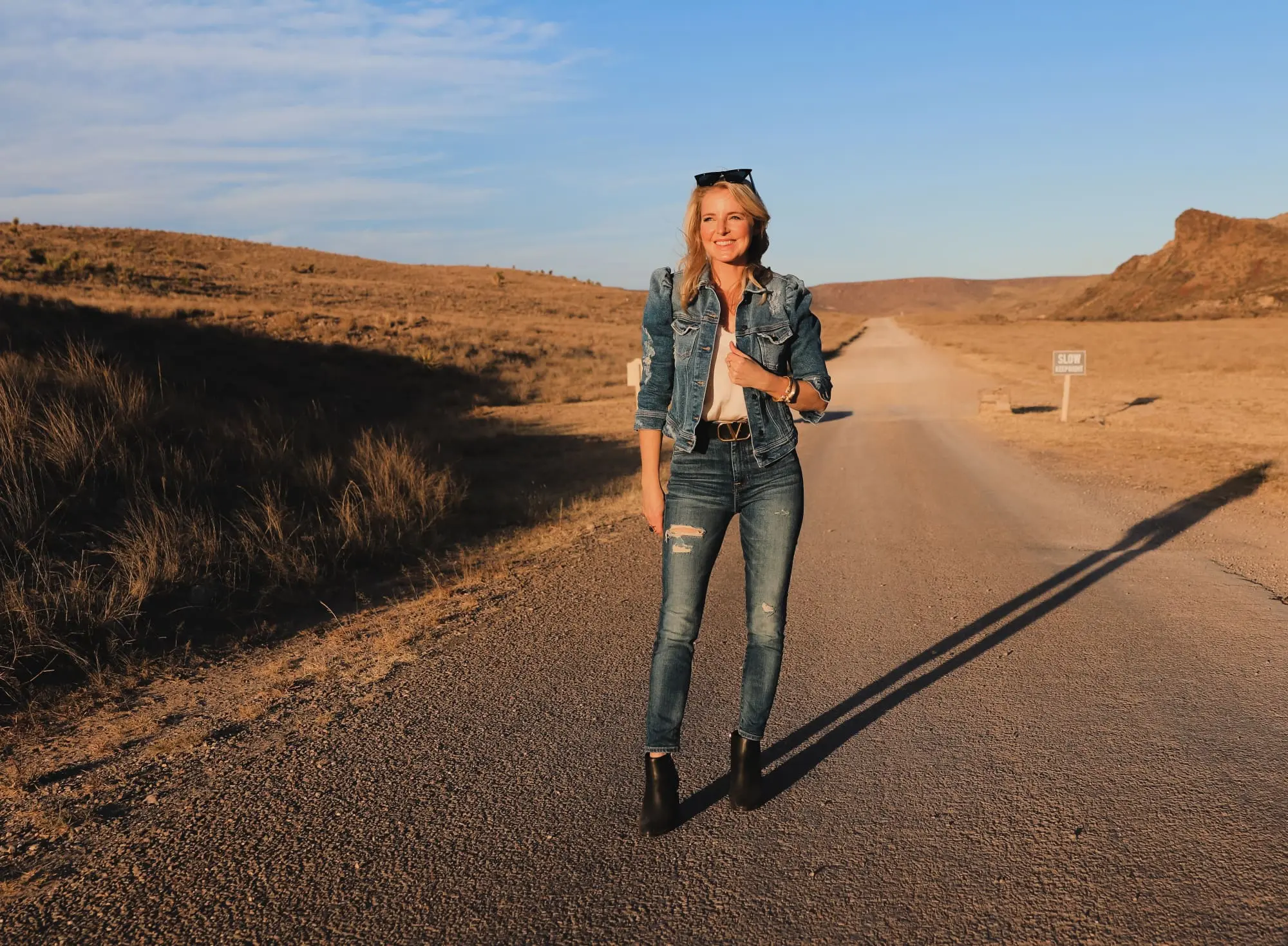 How To Wear Denim on Denim, Erin Busbee of Busbee wearing a distressed puff sleeve denim jacket by Retrofete, 7 For All Mankind distressed jeans, black Alexander Wang cutout booties, white B.P. lace cami, black cat eye sunglasses, and Julie Vos gold cuff bracelets in West Texas