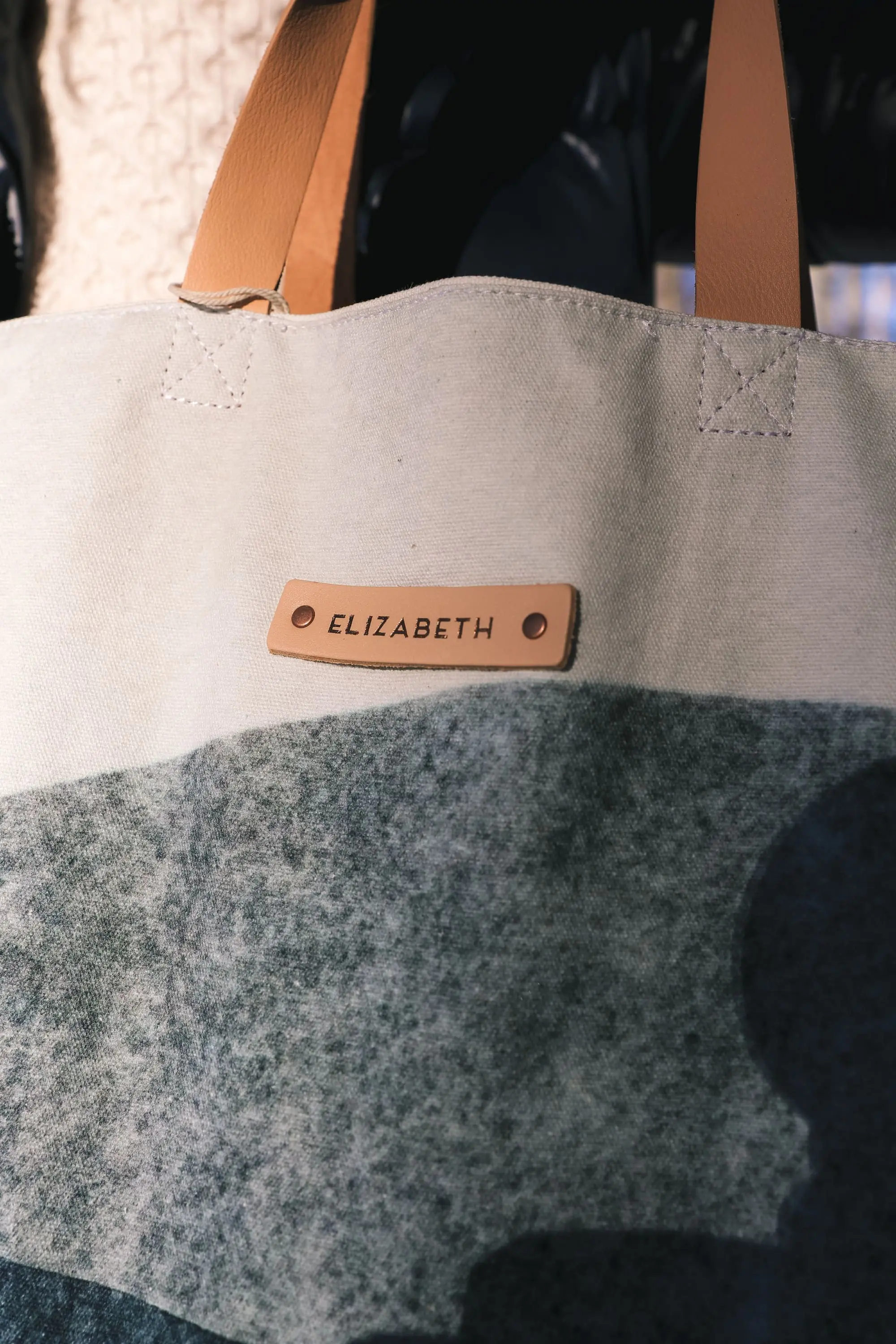 Personalized Gifts, Erin Busbee of Busbee Style carrying a blue and white personalized tote bag from Minted wearing a SAM. puffer jacket with a cable knit sweater and jeans in Telluride, Colorado