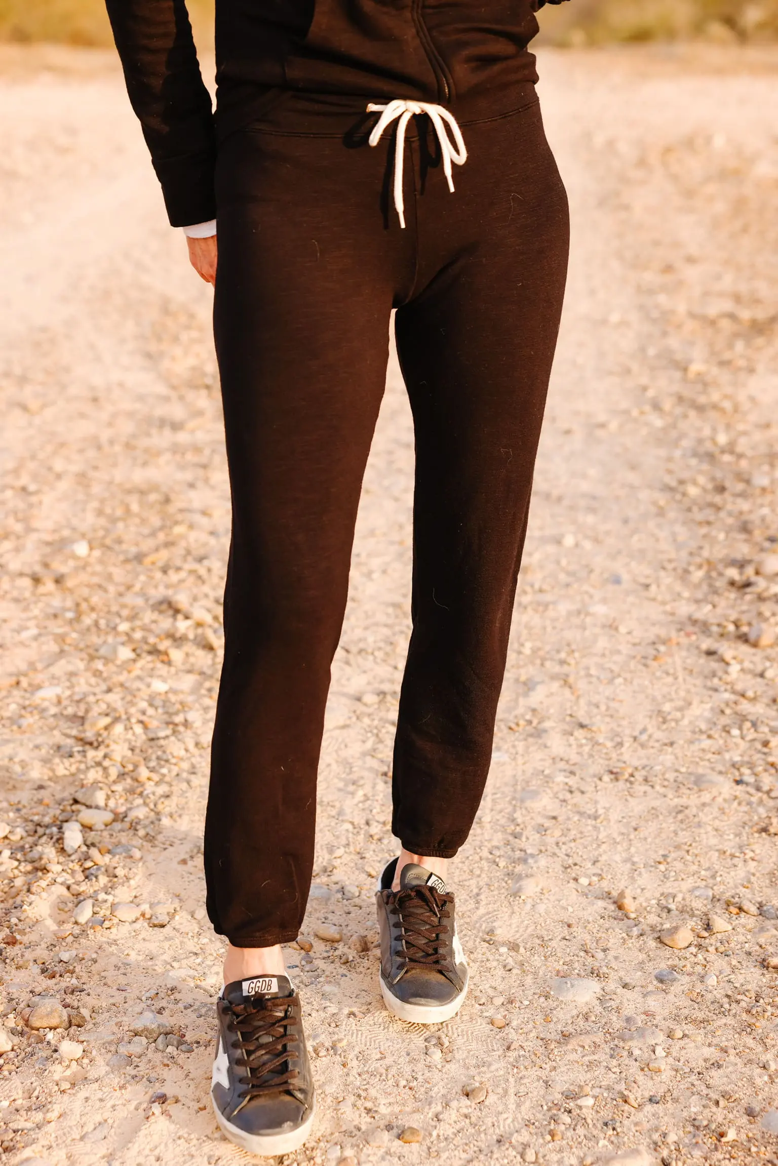 Cozy Loungewear, Erin Busbee of Busbee wearing a black hoodie by Monrow over a white long sleeve tee by Free People tucked into black drawstring joggers by Monrow and black Golden Goose sneakers in south Texas