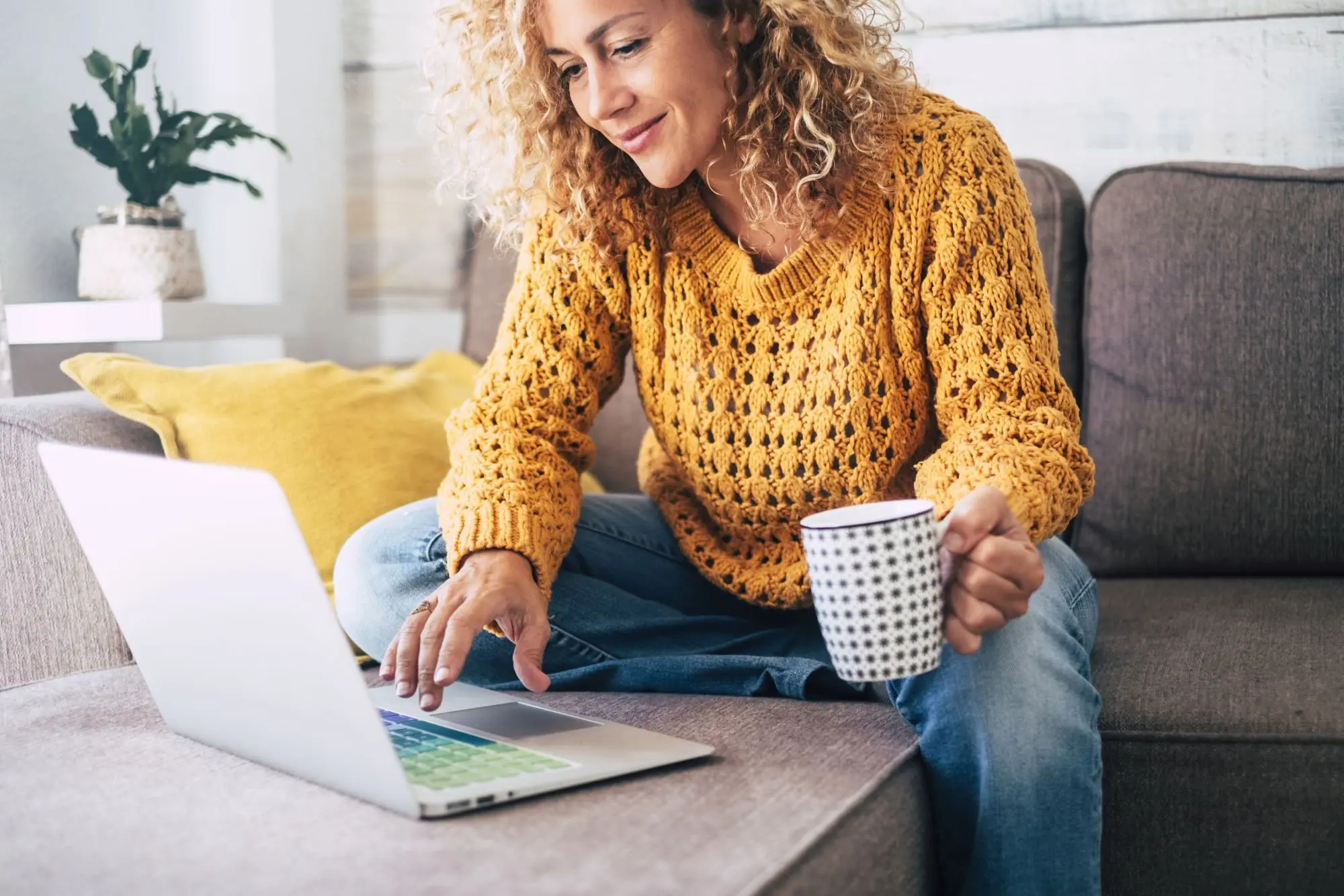 dating profile after 40, woman on sofa relaxing with coffee and typing on computer