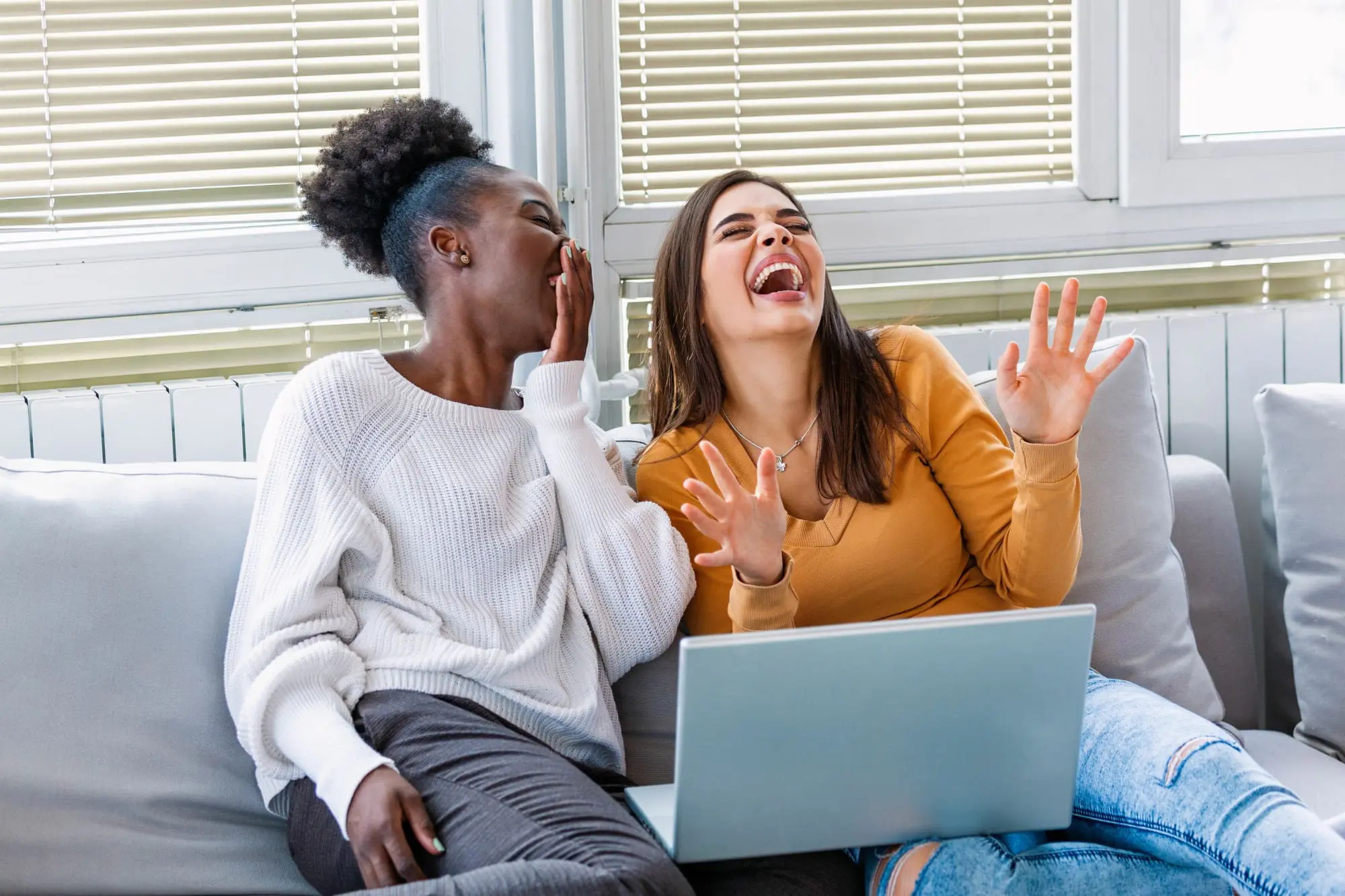 dating profile after 40, two women on sofa with laptop laughing having fun