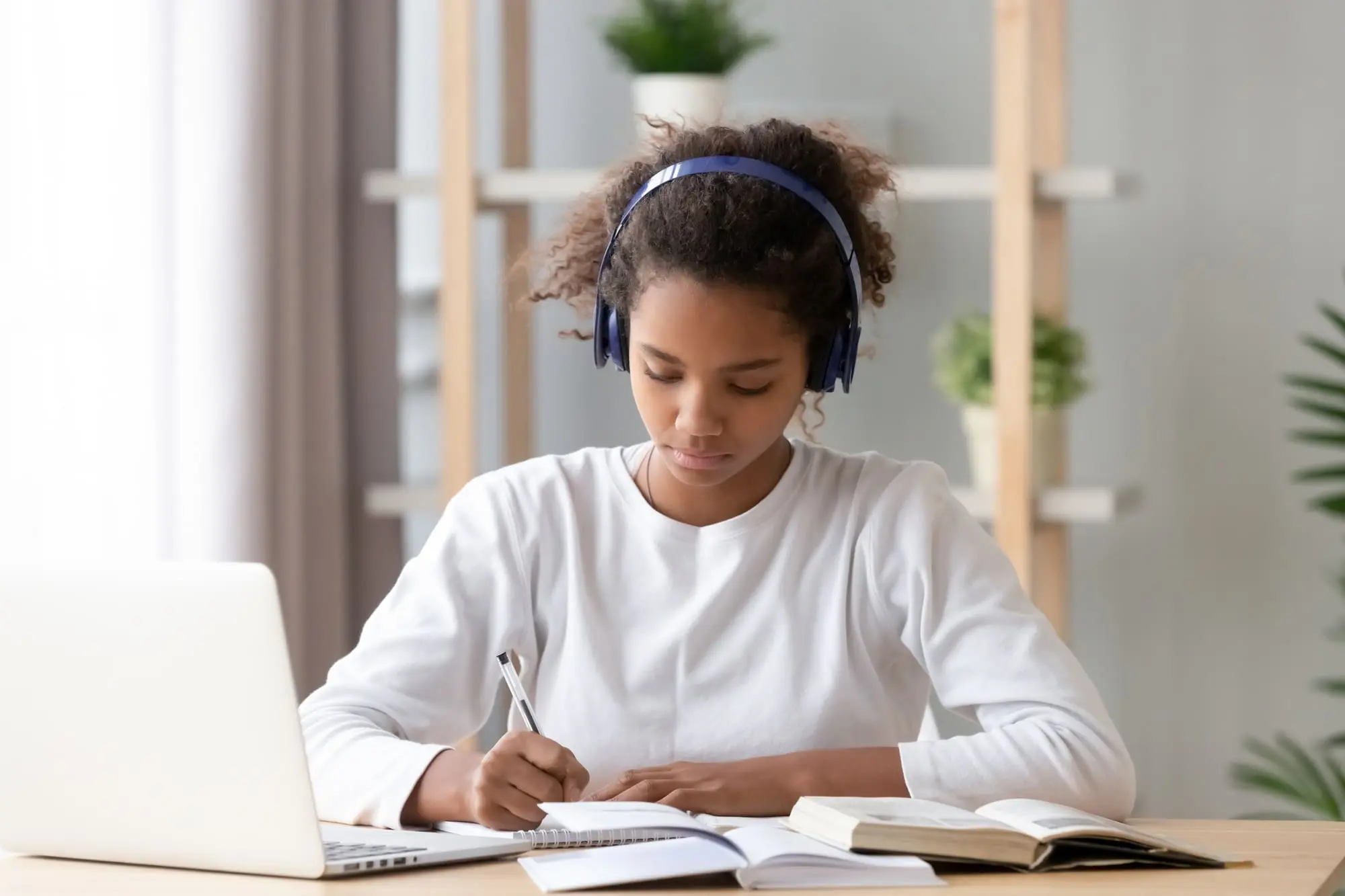 budget for when you have teens, African American girl doing homework with headphones and a laptop