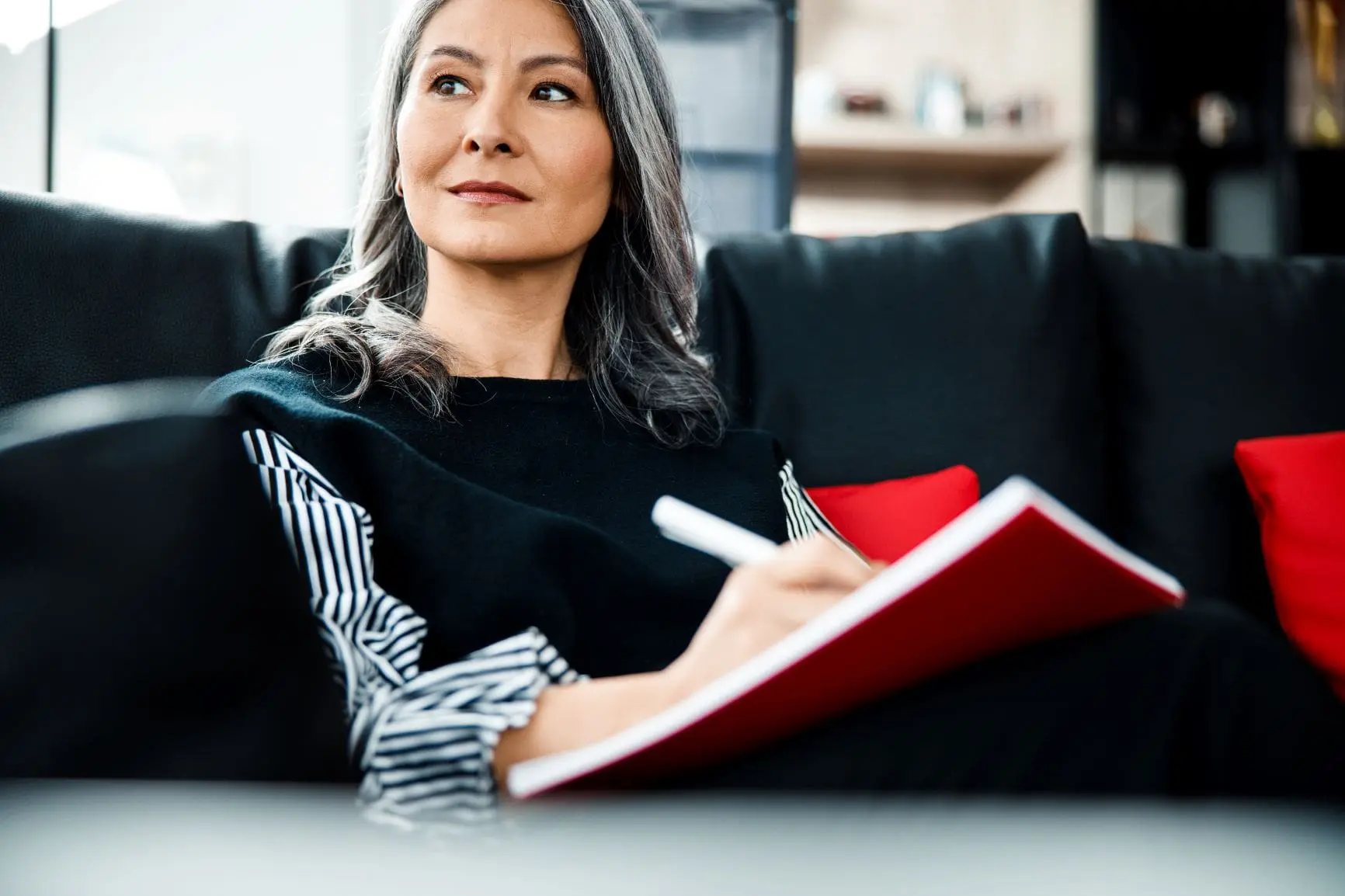 Asian woman in black & white writing in red journal, manifestation for beginners, manifest your dream life