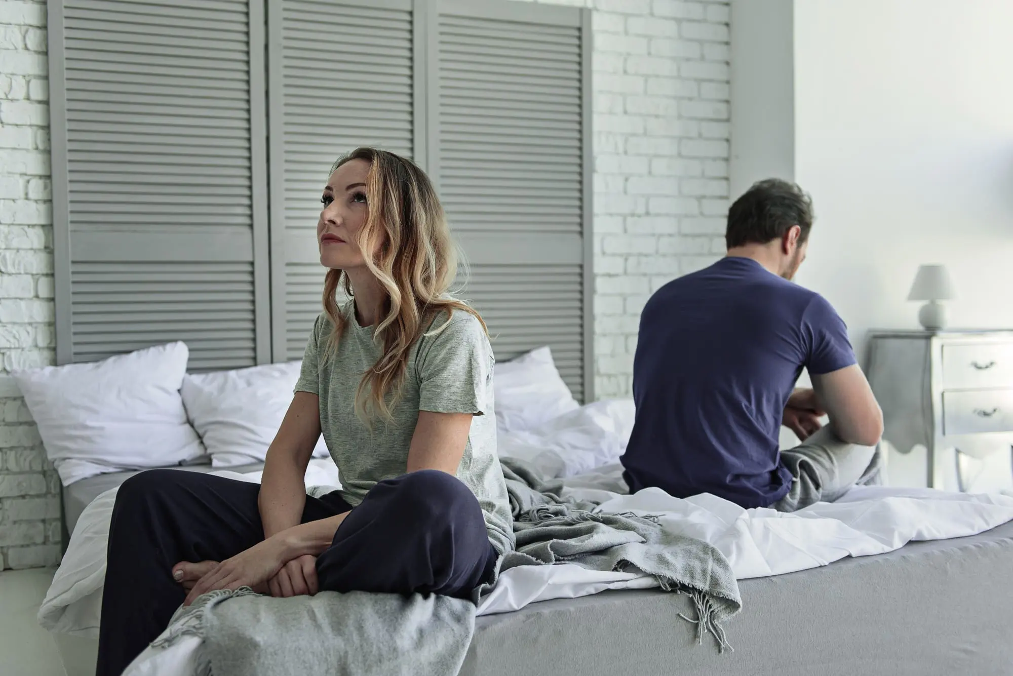 fighting fairly in your relationship, couple sitting on their bed facing away from each other not speaking