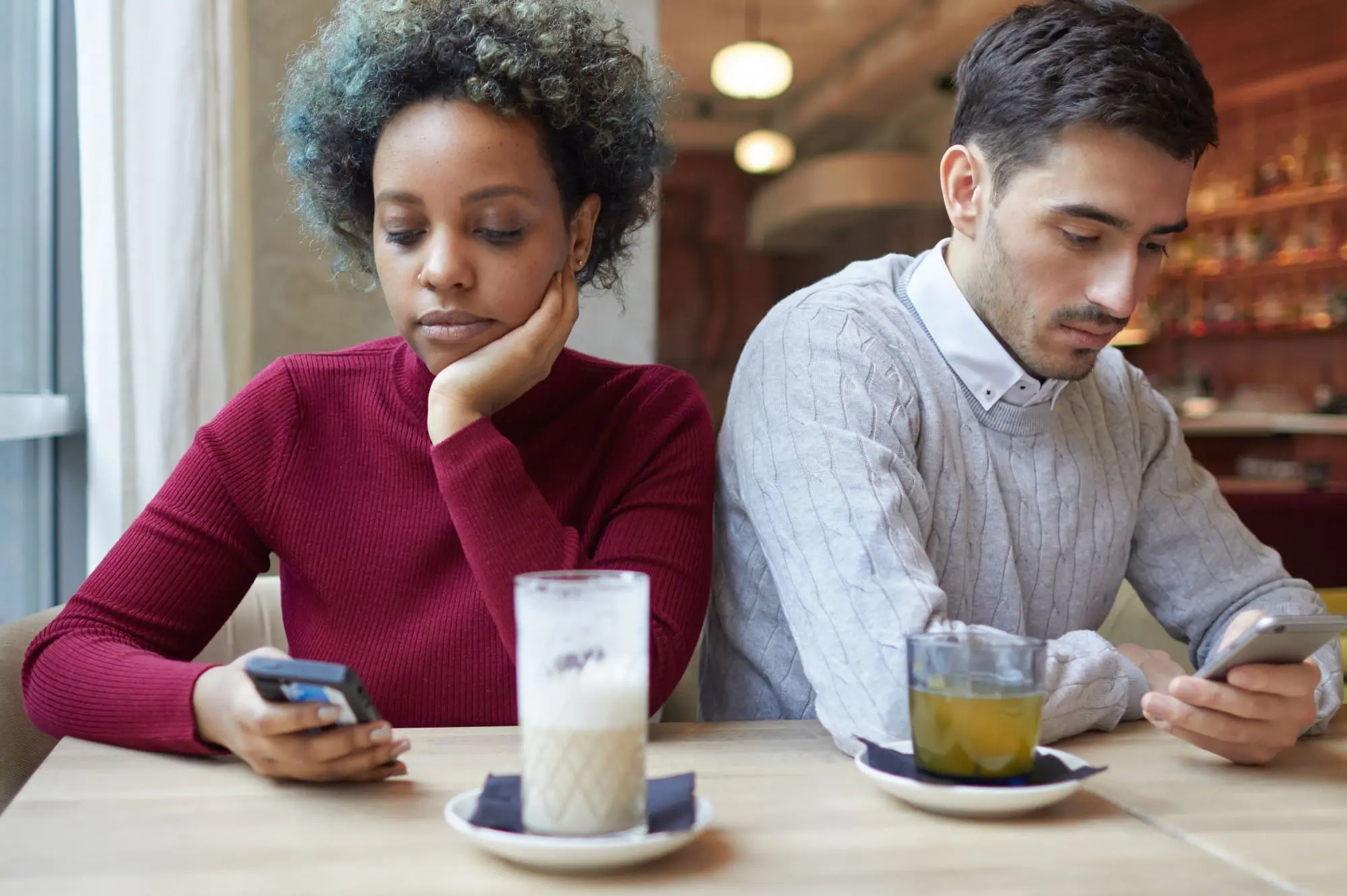 fighting fairly in your relationship, African American woman and white man, couple, looking at their cell phones