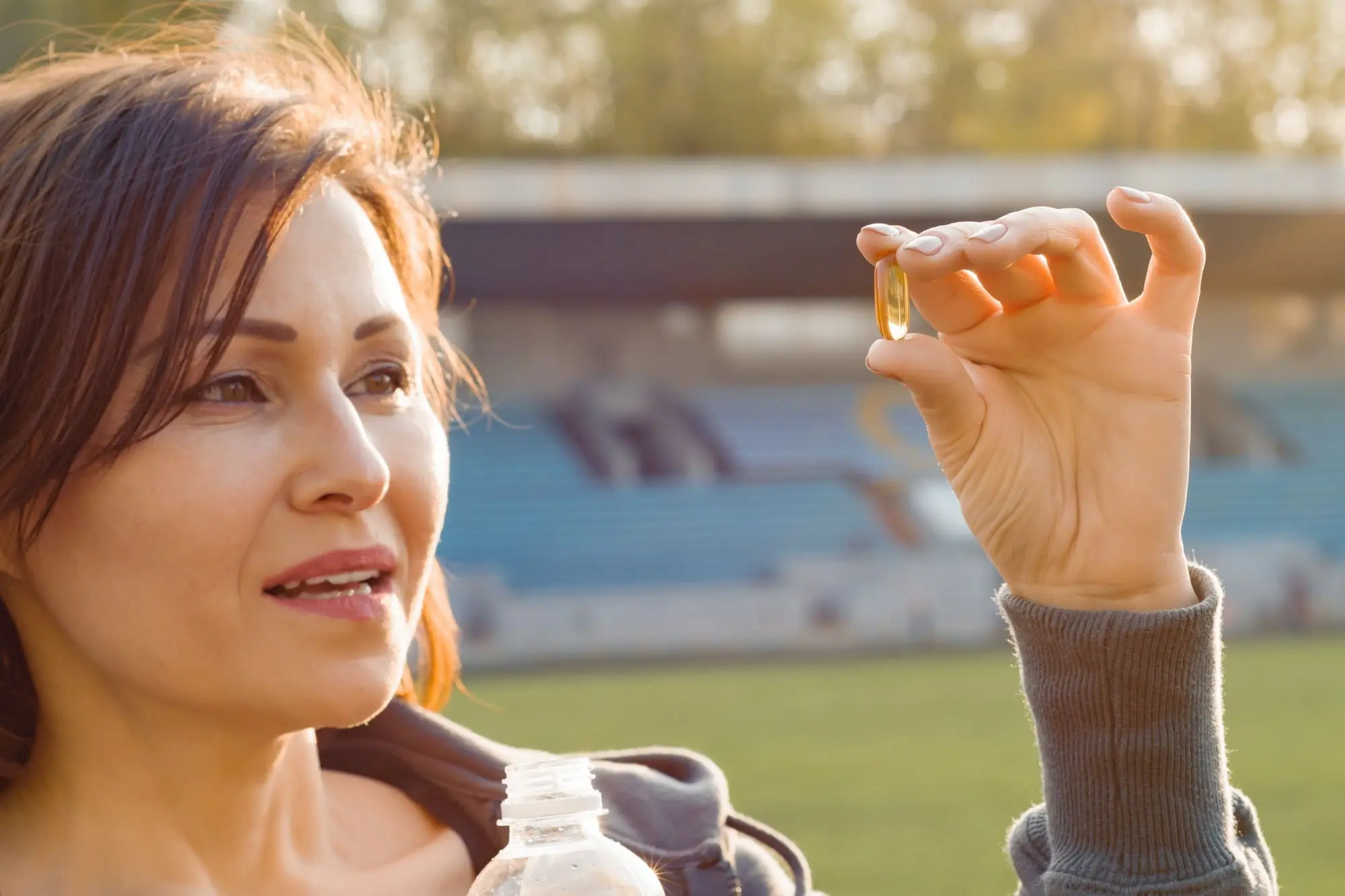 Going Through Menopause? You Should Try Vitamin K2, Dark-haired middle-aged woman taking supplement outside