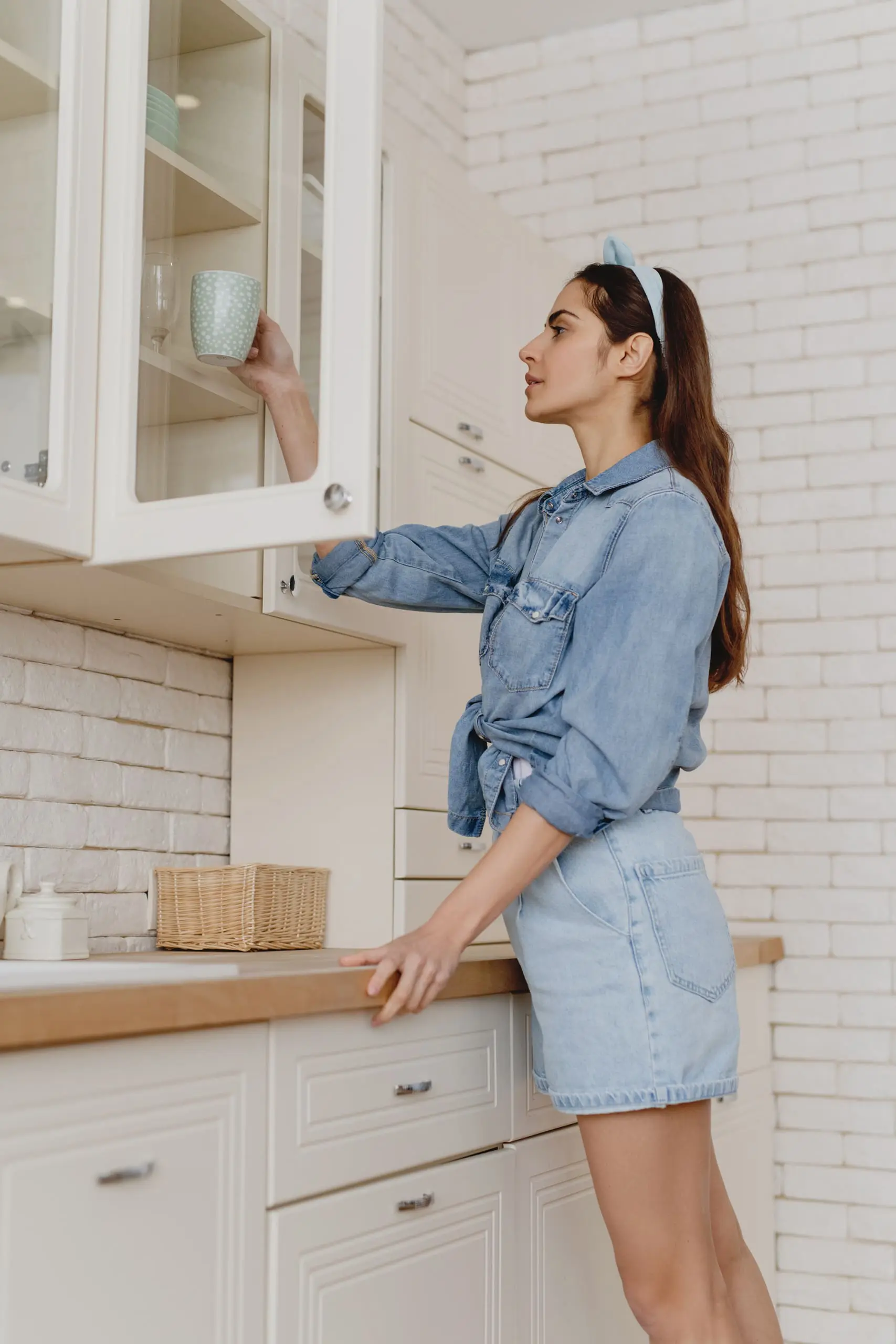 common menopause questions, Long-haired brunette in denim putting mug away in white kitchen