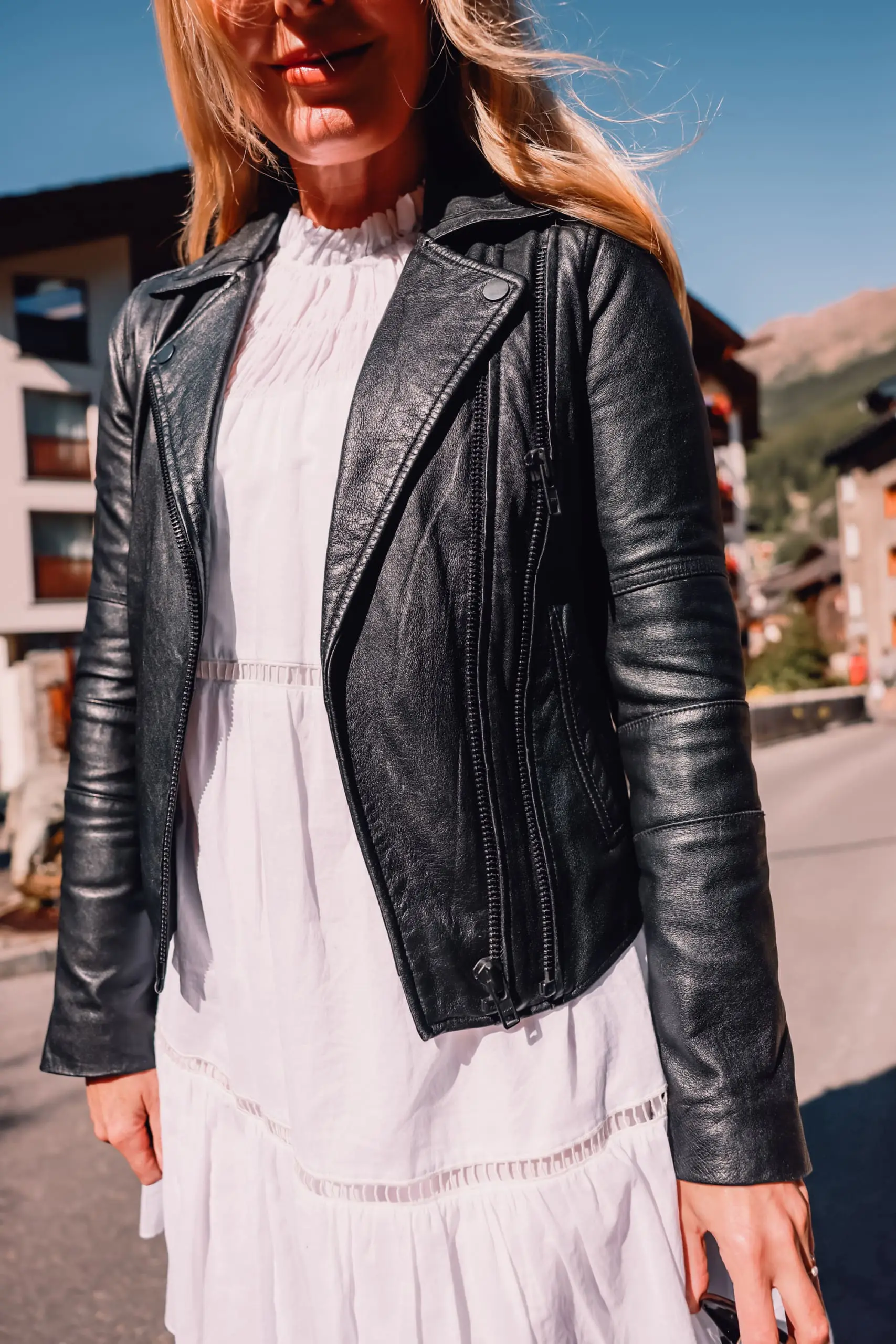 ways to wear a moto jacket, how to wear a moto jacket, moto jackets over 40, how to wear a moto jacket over 40, wearing moto jackets, how to style a moto jacket over 40, erin busbee, black leather moto jacket, white michael kors dress, black Paige side zip booties, zermatt switzerland