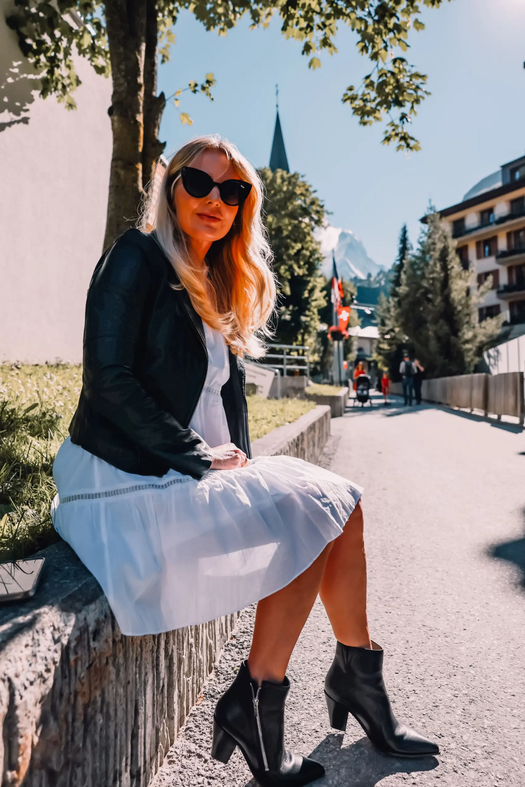 ways to wear a moto jacket, how to wear a moto jacket, moto jackets over 40, how to wear a moto jacket over 40, wearing moto jackets, how to style a moto jacket over 40, erin busbee, black leather moto jacket, white michael kors dress, black Paige side zip booties, zermatt switzerland