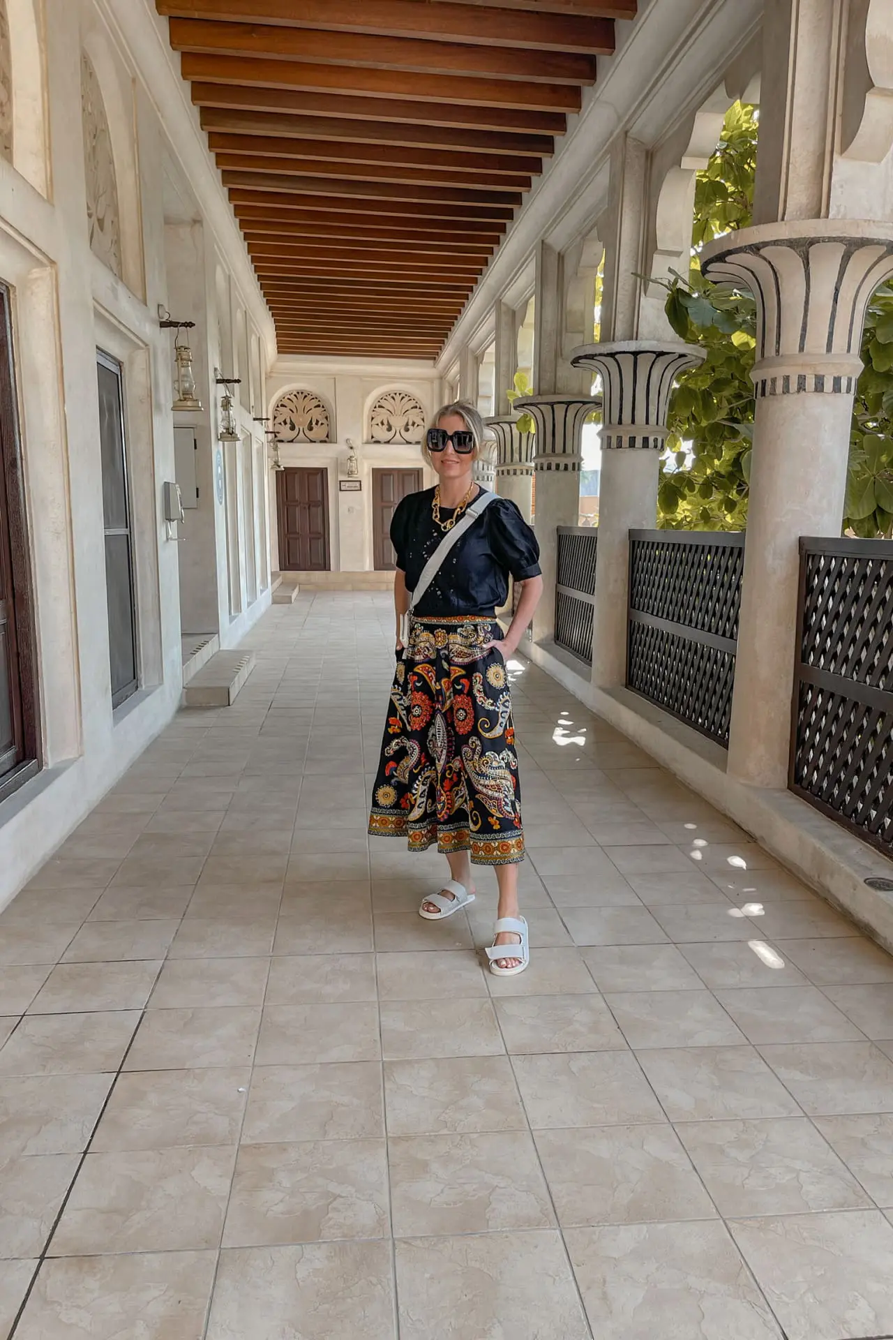 planning a trip to the middle east, where to go in the middle east, how to plan a trip to the middle east, dubai, united arab emirates, UAE, erin busbee, busbee style, busbee family travels, dubai city tour, touring old town dubai, alice + olivia embroidered skirt, ba&sh black blouse, prada raffia triangle bag, mercedes castillo white slides, gucci sunglasses, paco rabanne gold chunky necklace