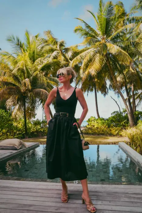 styled black dress for vacation with beige heels and black belt