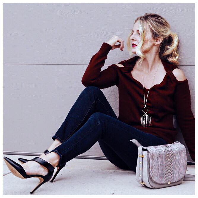 Cold shoulder cashmere burgundy sweater with dark wash skinny jeans and black pumps, a gray python saddle bag and gold alexis bitter pendant necklace from neiman marcus last call