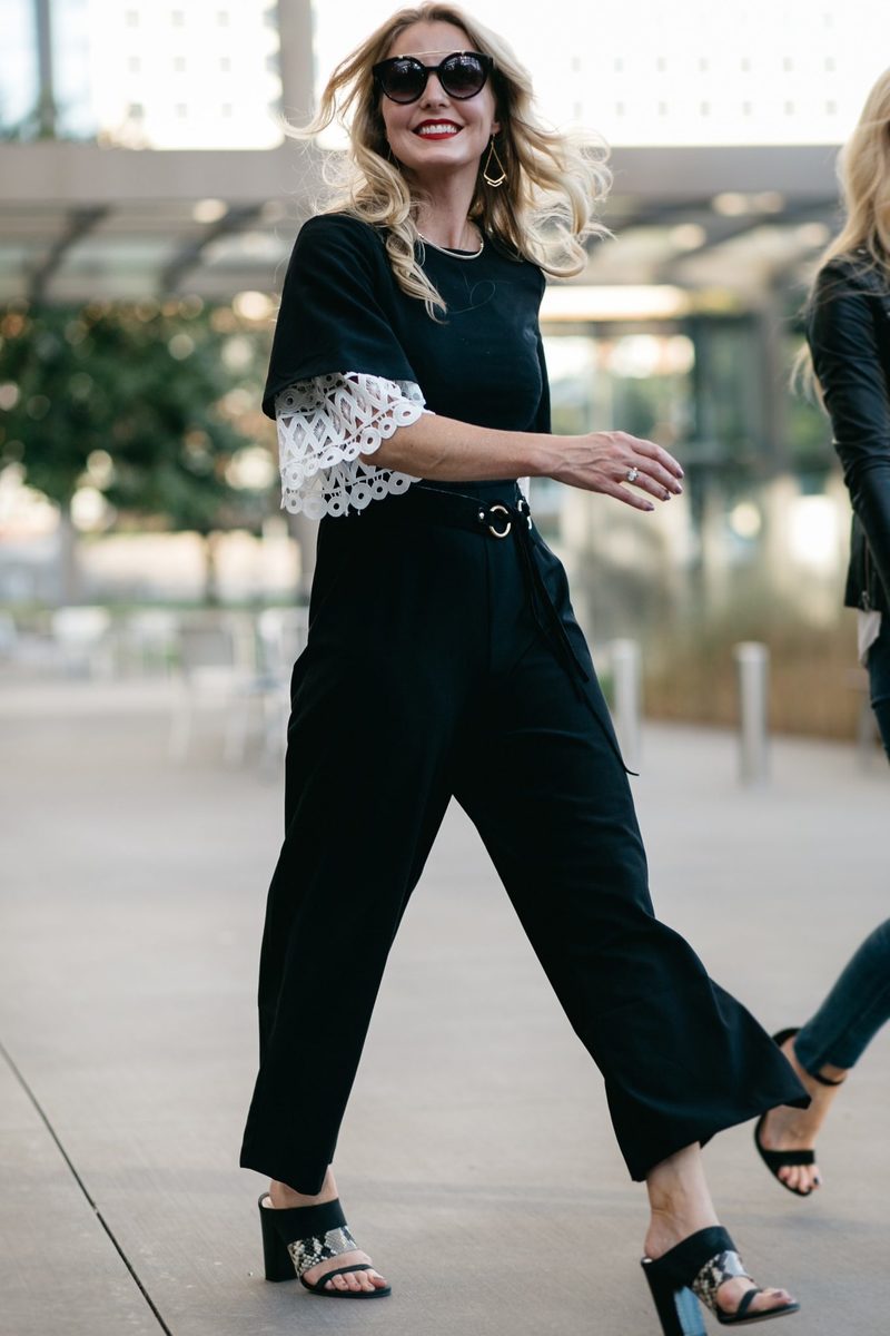 Asks black jumpsuit with wide leg over a crochet white top with black sunglasses and a black leather moto jacket by joie