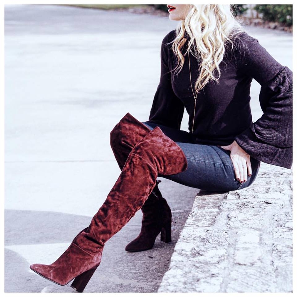 wardrobe stylist erin busbee sitting down wearing tall burgundy suede boots by marc fisher and a bell sleeve sweater in navy by olivia palermo for chelsea28