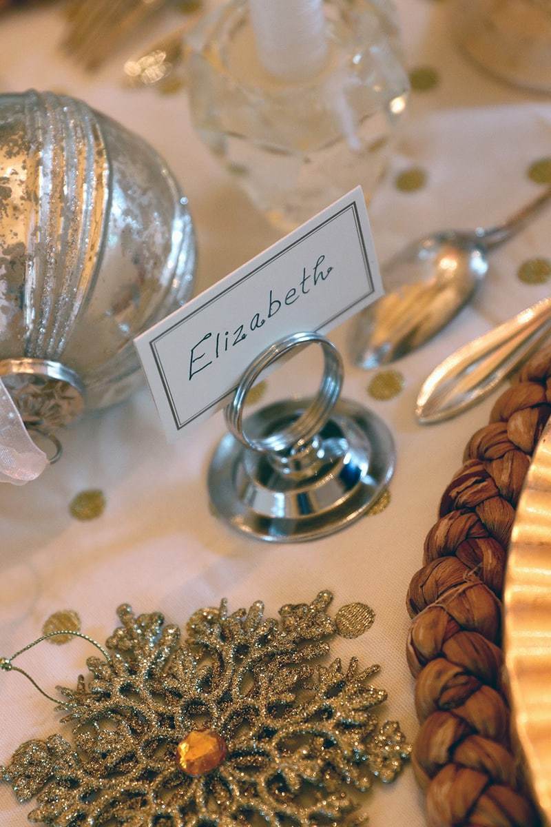 a place card idea using gift tags and ornaments on the table runner to add some sparkle to your holiday table