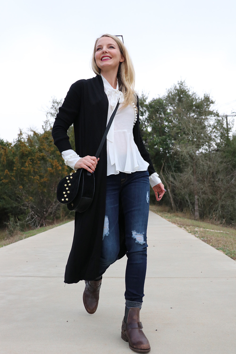 erin busbee from busbeestyle.com walking down path wearing black long cardigan from neiman marcus last call with white bow blouse