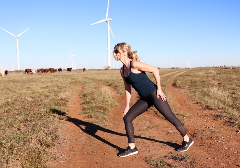 erin busbee, fitness, fashion, beauty blogger, running in the air, wearing zella exercise top and pants and under armour running sneakers stretching 