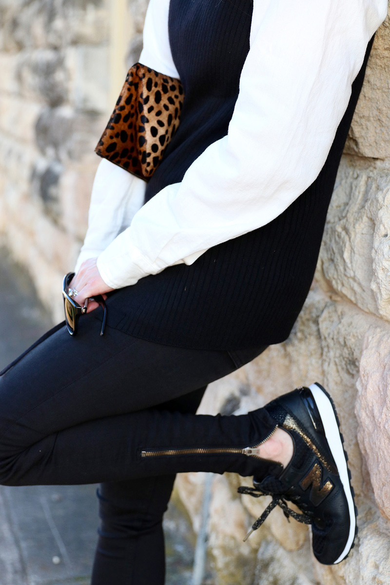 black and gold new balance sneakers add a sporty twist to a sweater and jeans. the claire v leopard clutch adds a pop of interest to the neutral color palette. This is one way to try the athleisure trend