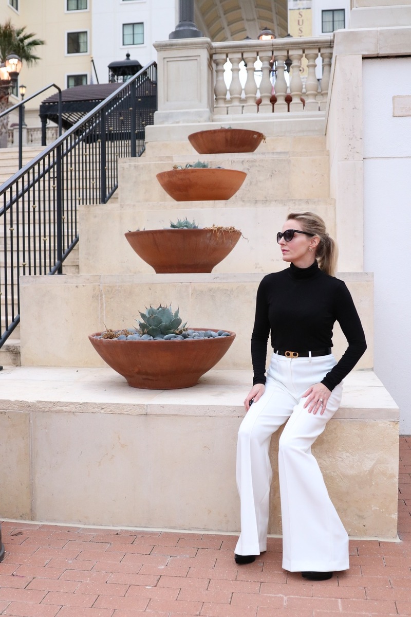 how to wear white in the winter to the office, 3 outfit ideas for the busy professional woman, this look features wide leg white trousers by milly and a classic black turtleneck with a reversible salvatore ferragamo belt