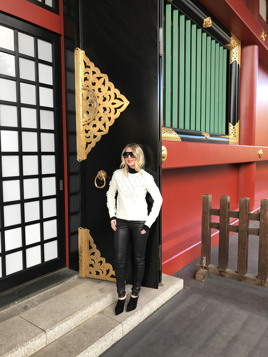 Erin busbee wearing a white topshop sweater with pom pom detailing, faux leather black skinny jeans by citizens of humanity called the "rocket" jeans, mules by marc fisher in black suede and flat top sunglasses that look like Givenchy but only cost $10 from Amazon fashion