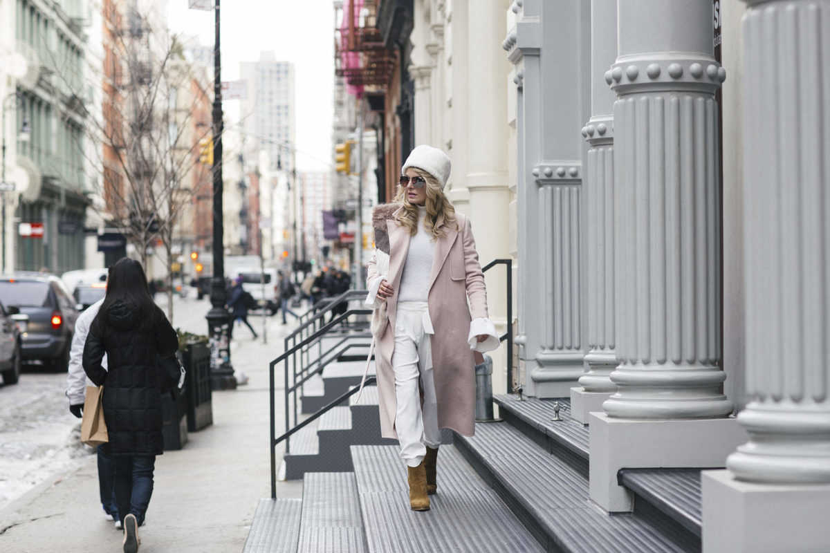 Erin Busbee at New York Fashion Week February 2017 wearing white parker new york jogging pants, with white cashmere turtleneck sweater, white faux fur pill box hat from New York & Company, faux fur wrap by Urbancode with Marc Fisher suede booties