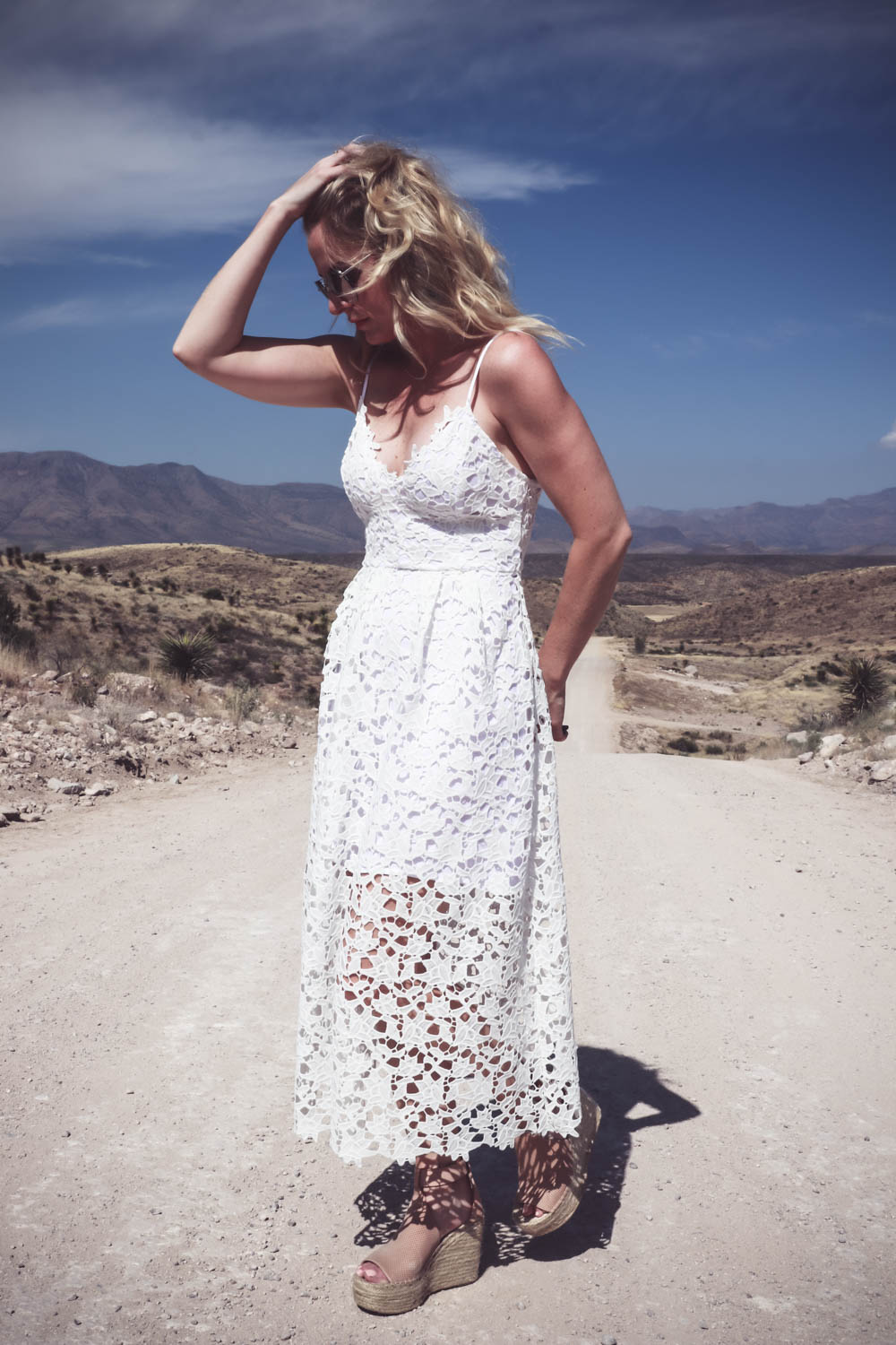 Fashion blogger and fashion youtuber, erin busbee of busbeestyle.com, wearing a white lace dress by ASTR, nude leather espadrille sandals by Marc Fisher (super comfortable) and the mirrored aviator sunglasses are by Quay Australia at Cibolo Creek Ranch in West Texas near Marfa
