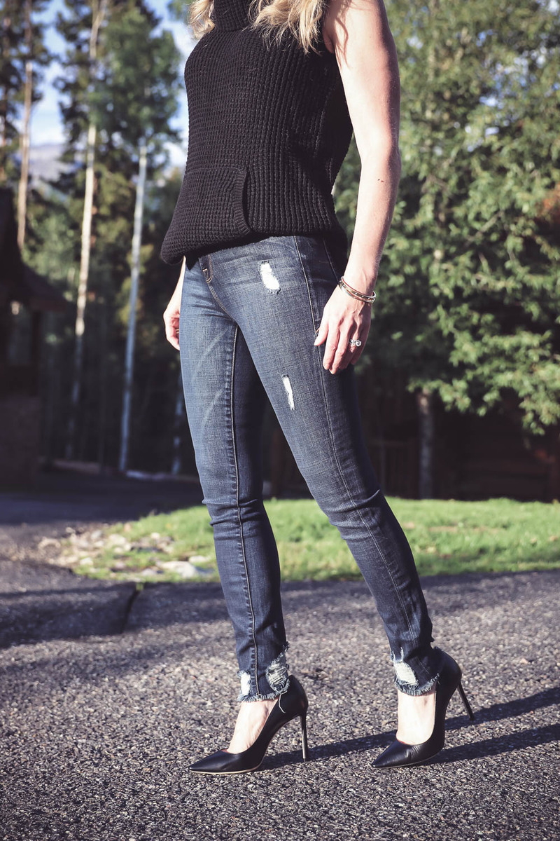 Denim Trends, Good American distressed jeans, high rise, distressed at ankle with black sleeveless sweater, and jimmy choo pumps