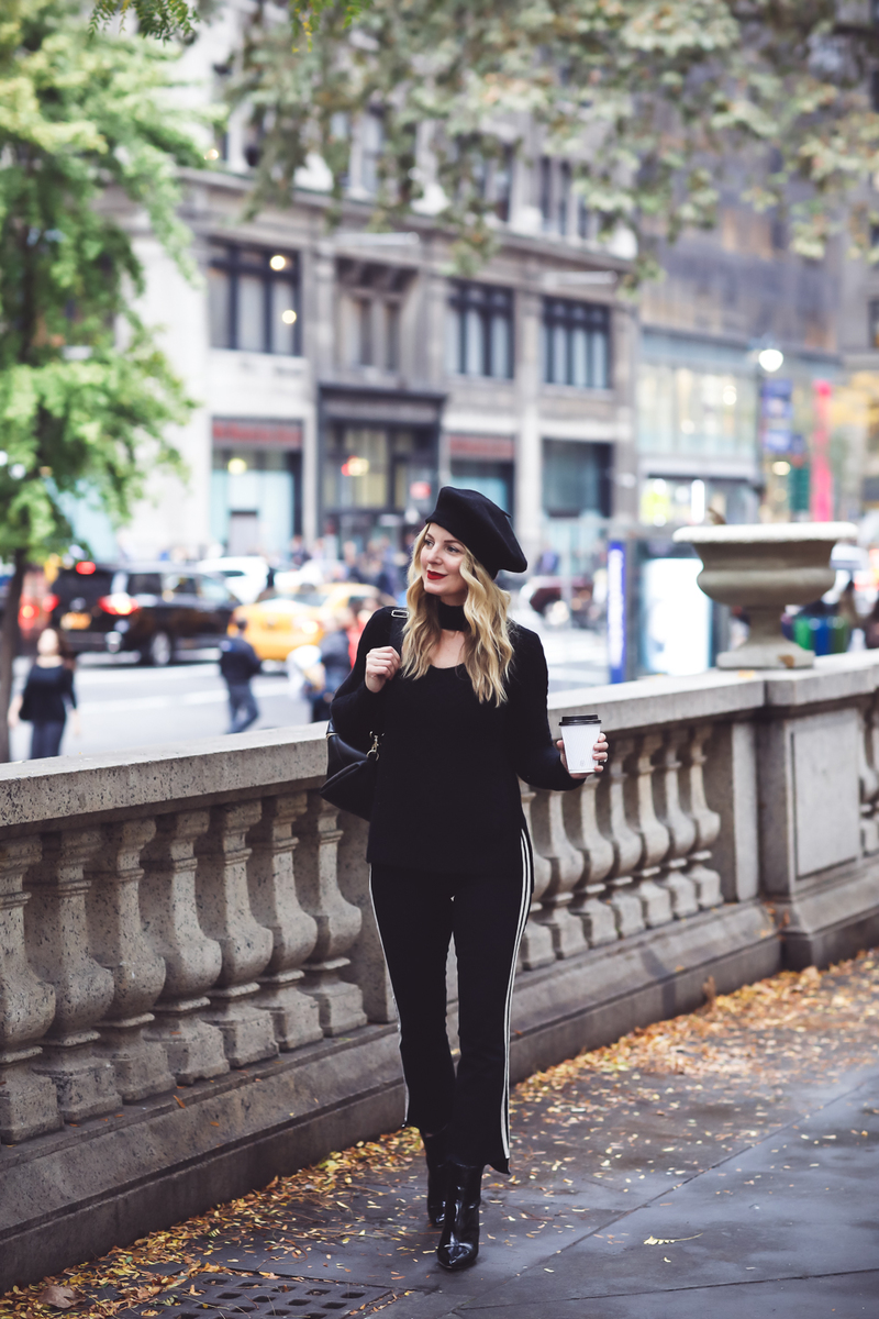 Beret, Fashion Blogger Erin Busbee of Busbee Style walking in New York City in an all black look with her cashmere beret, Mother racing stripe jeans, a choker cashmere black sweater by Aqua from Bloomingdales, her Jetsetter black leather backpack from Henri Bendel and black patent ankle boots by Vince Camuto