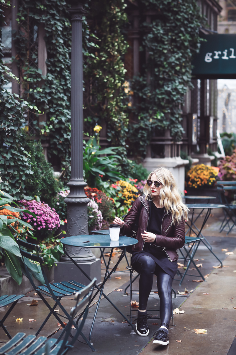 Sweatshirt Dress with corset waist in black by Socialite paired with a Doma leather hooded moto jacket, Spanx faux leather leggings and Kenneth Cole black patent sneakers on Fashion Blogger, Erin Busbee of Busbee Style at Bryant Park in New York City