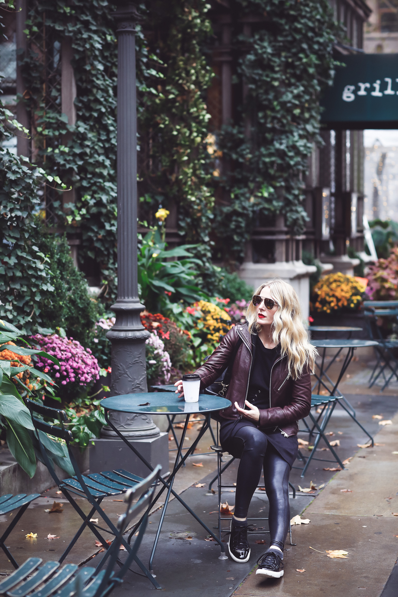 Sweatshirt Dress with corset waist in black by Socialite paired with a Doma leather hooded moto jacket, Spanx faux leather leggings and Kenneth Cole black patent sneakers on Fashion Blogger, Erin Busbee of Busbee Style at Bryant Park in New York City