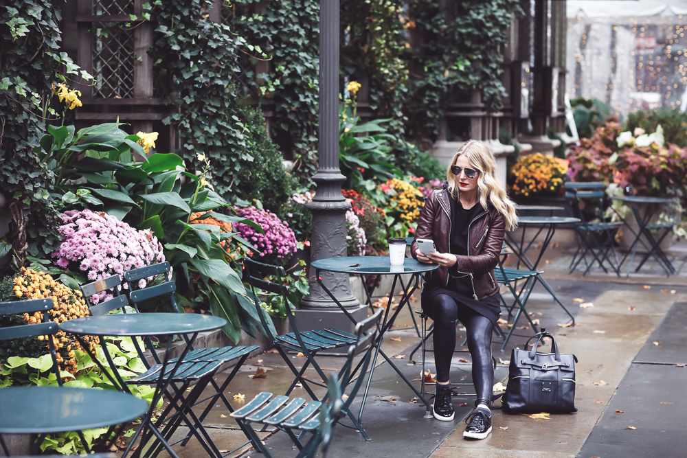 Sweatshirt Dress with corset waist in black by Socialite paired with a Doma leather hooded moto jacket, Spanx faux leather leggings and Kenneth Cole black patent sneakers on Fashion Blogger, Erin Busbee of Busbee Style at Bryant Park in New York City